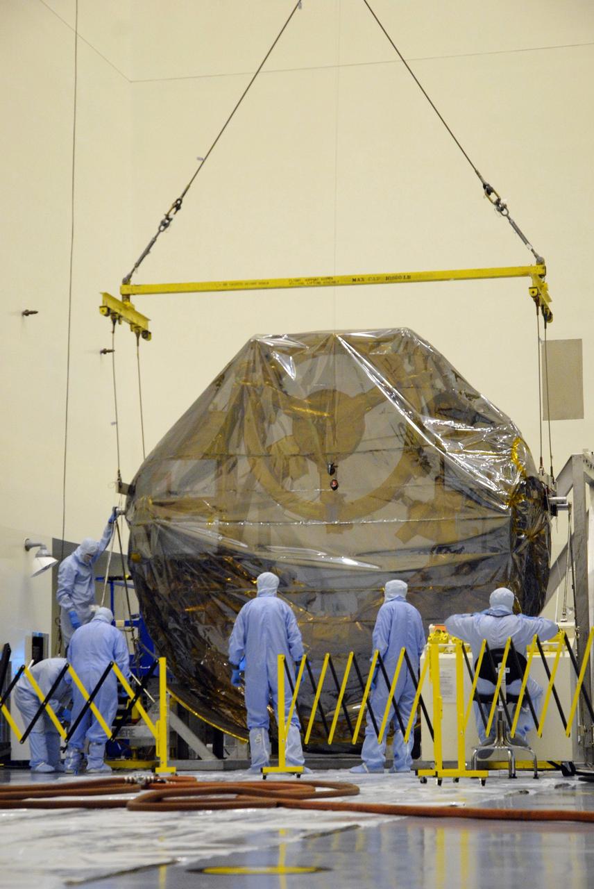 CAPE CANAVERAL, Fla. –  In the Payload Hazardous Servicing Facility at NASA's Kennedy Space Center, workers get ready to release the crane that lowered the ground support equipment for the STS-125 Hubble Servicing Mission onto a work stand. The GSE are carriers, or pallets, that will hold equipment in space shuttle Atlantis’ payload bay.  Under the protective covering of the carrier can be seen the soft capture mechanism.  The carrier will be moved to a work stand. The carriers will be prepared for the integration of telescope science instruments, both internal and external replacement components, as well as the flight support equipment to be used by the astronauts during the servicing mission.  The three payload carriers or pallets are the Flight Support System, the Super Lightweight Interchangeable Carrier and the Orbital Replacement Unit Carrier.  At the end of July, a fourth and final carrier, the Multi-Use Lightweight Equipment carrier will join the others in the Payload Hazardous Servicing Facility where the Hubble payload is being prepared for launch. Photo credit: NASA/Cory Huston