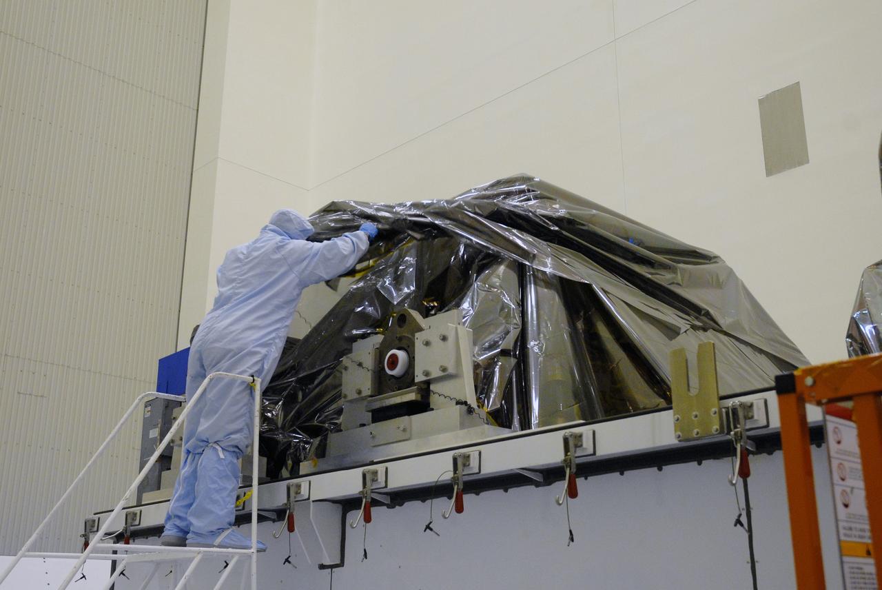 CAPE CANAVERAL, Fla. –  In the Payload Hazardous Servicing Facility at NASA's Kennedy Space Center, a worker looks under the protective covering at the hardware for space shuttle Atlantis' STS-125 mission to NASA's Hubble Space Telescope.  The container holds the Super Lightweight Interchangeable Carrier, or SLIC, and the Orbital Replacement Unit Carrier, or ORUC. Another payload carrier, the Flight Support System, has already been delivered,  and the Multi-Use Lightweight Equipment carrier will be delivered in late July. The carriers will be prepared for the integration of telescope science instruments, both internal and external replacement components, as well as the flight support equipment to be used by the astronauts during the Hubble servicing mission, targeted for launch Oct. 8.  Photo credit: NASA/Jack Pfaller