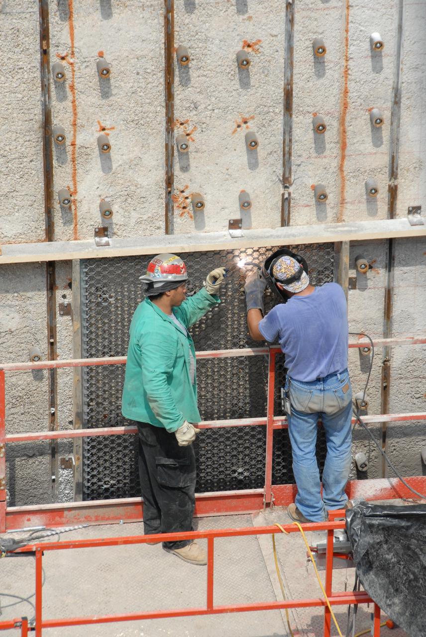 CAPE CANAVERAL, Fla. – Workers weld a steel grid structure to the wall of the flame trench on Launch Pad 39A at NASA's Kennedy Space Center. Damage to the trench occurred during the launch of Discovery on the STS-124 mission. A 75- by 20-foot section of the east wall was destroyed and debris scattered as far as the pad perimeter fence. Repairs are expected to be completed before the targeted Oct. 8 launch of Atlantis on the NASA Hubble Space Telescope servicing mission. Photo credit: NASA/Jack Pfaller