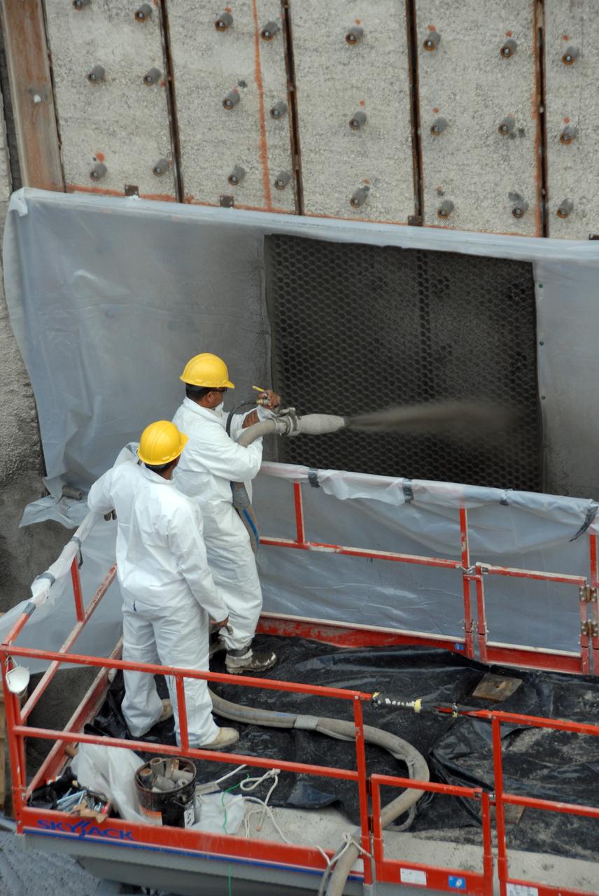 CAPE CANAVERAL, Fla. – At Launch Pad 39A at NASA's Kennedy Space Center, workers spray a heat-resistant concrete called Fondue Fyre into steel grid structures, welded to the wall of the flame trench. Fondue Fyre was developed during NASA's Apollo lunar program. Damage to the trench occurred during the May 31 launch of Discovery on the STS-124 mission. A 75- by 20-foot section of the east wall was destroyed and debris scattered as far as the pad perimeter fence. Repairs are expected to be completed before the targeted Oct. 8 launch of Atlantis on the NASA Hubble Space Telescope servicing mission. Photo credit: NASA/Jack Pfaller