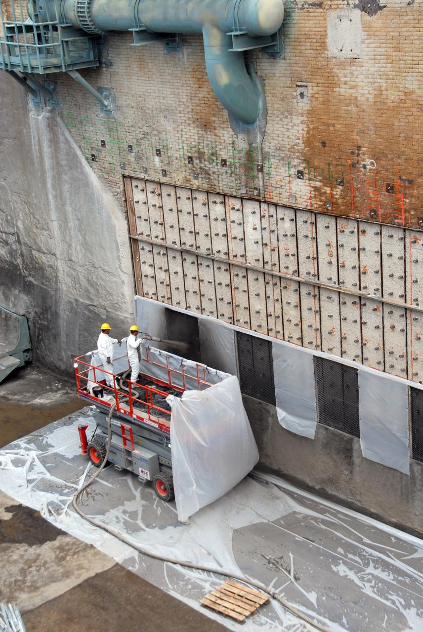 CAPE CANAVERAL, Fla. – At Launch Pad 39A at NASA's Kennedy Space Center, workers on a platform spray a heat-resistant concrete called Fondue Fyre into steel grid structures, welded to the wall of the flame trench. Fondue Fyre was developed during NASA's Apollo lunar program. Damage to the trench occurred during the May 31 launch of Discovery on the STS-124 mission. A 75- by 20-foot section of the east wall was destroyed and debris scattered as far as the pad perimeter fence. Repairs are expected to be completed before the targeted Oct. 8 launch of Atlantis on the NASA Hubble Space Telescope servicing mission. Photo credit: NASA/Jack Pfaller