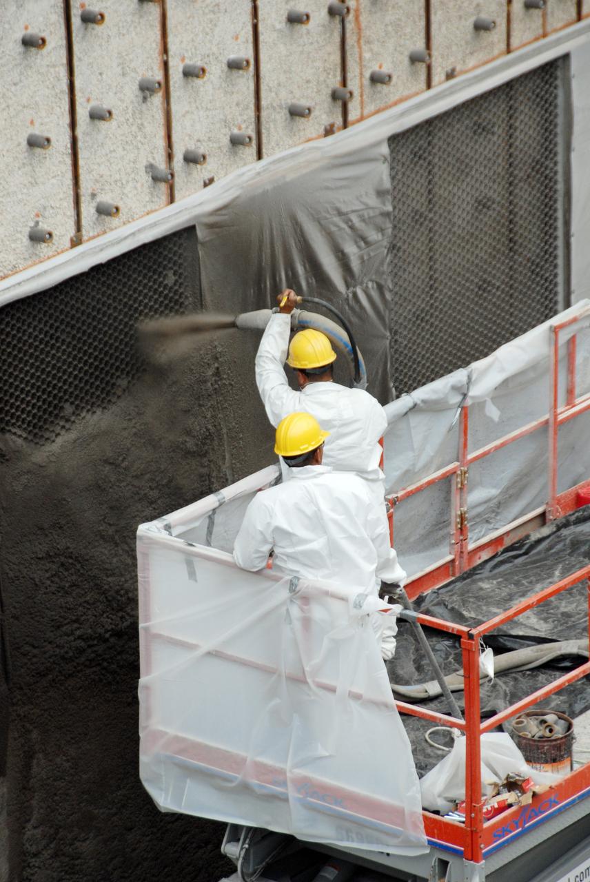 CAPE CANAVERAL, Fla. – At Launch Pad 39A at NASA's Kennedy Space Center, workers spray a heat-resistant concrete called Fondue Fyre into steel grid structures, welded to the wall of the flame trench. Fondue Fyre was developed during NASA's Apollo lunar program. Damage to the trench occurred during the May 31 launch of Discovery on the STS-124 mission. A 75- by 20-foot section of the east wall was destroyed and debris scattered as far as the pad perimeter fence. Repairs are expected to be completed before the targeted Oct. 8 launch of Atlantis on the NASA Hubble Space Telescope servicing mission. Photo credit: NASA/Jack Pfaller