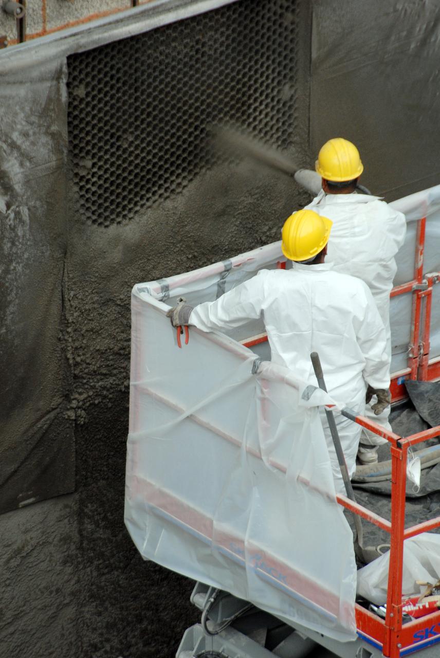 CAPE CANAVERAL, Fla. – At Launch Pad 39A at NASA's Kennedy Space Center, workers spray a heat-resistant concrete called Fondue Fyre into steel grid structures, welded to the wall of the flame trench. Fondue Fyre was developed during NASA's Apollo lunar program. Damage to the trench occurred during the May 31 launch of Discovery on the STS-124 mission. A 75- by 20-foot section of the east wall was destroyed and debris scattered as far as the pad perimeter fence. Repairs are expected to be completed before the targeted Oct. 8 launch of Atlantis on the NASA Hubble Space Telescope servicing mission. Photo credit: NASA/Jack Pfaller