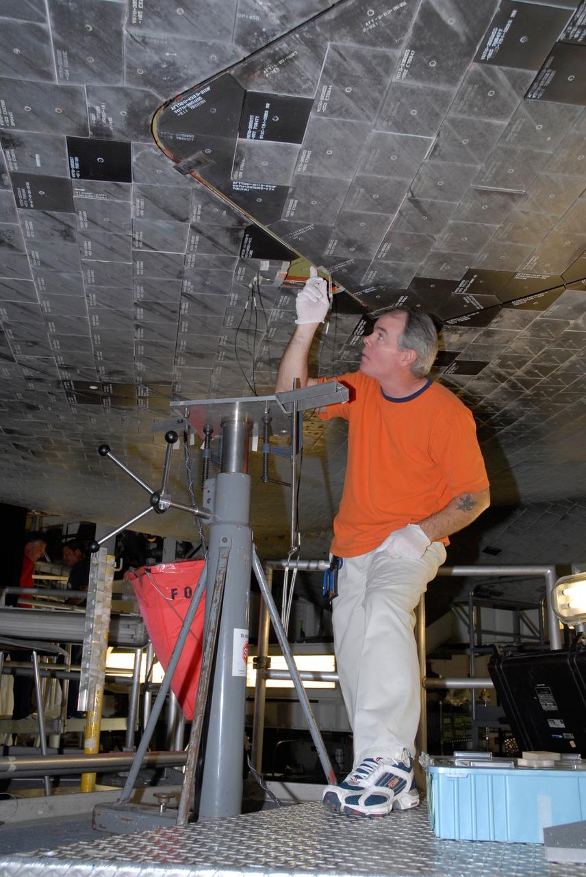CAPE CANAVERAL, Fla. – Inside Orbiter Processing Facility 2 at NASA's Kennedy Space Center, a United Space Alliance technician installs Boeing Replacement Insulation 18, or BRI-18, tile on space shuttle Endeavour during processing activities. BRI-18 is the strongest material used for thermal insulation on the orbiters and, when coated to produce toughened unipiece fibrous insulation, provides a tile with extremely high-impact resistance. It is replacing other tiles on areas of the vehicle where impact risk is high, such as the landing gear doors, the wing leading edge and the external tank doors. Endeavour will deliver a multi-purpose logistics module to the International Space Station on its STS-126 mission. Launch is targeted for Nov. 10.  Photo credit: NASA/Jack Pfaller