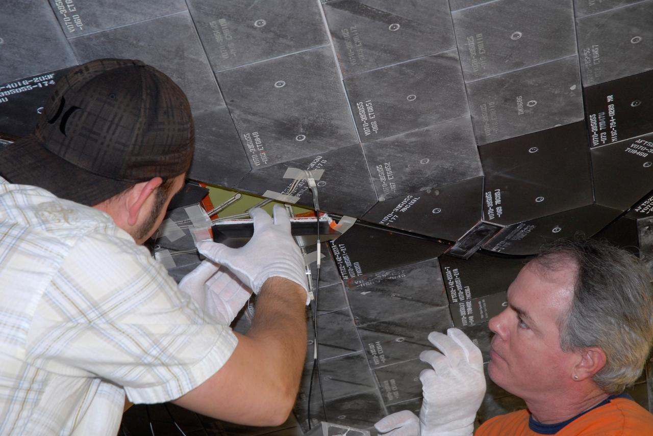 CAPE CANAVERAL, Fla. – Inside Orbiter Processing Facility 2 at NASA's Kennedy Space Center, United Space Alliance technicians install Boeing Replacement Insulation 18, or BRI-18, tile on space shuttle Endeavour during processing activities. BRI-18 is the strongest material used for thermal insulation on the orbiters and, when coated to produce toughened unipiece fibrous insulation, provides a tile with extremely high-impact resistance. It is replacing other tiles on areas of the vehicle where impact risk is high, such as the landing gear doors, the wing leading edge and the external tank doors. Endeavour will deliver a multi-purpose logistics module to the International Space Station on its STS-126 mission. Launch is targeted for Nov. 10.  Photo credit: NASA/Jack Pfaller