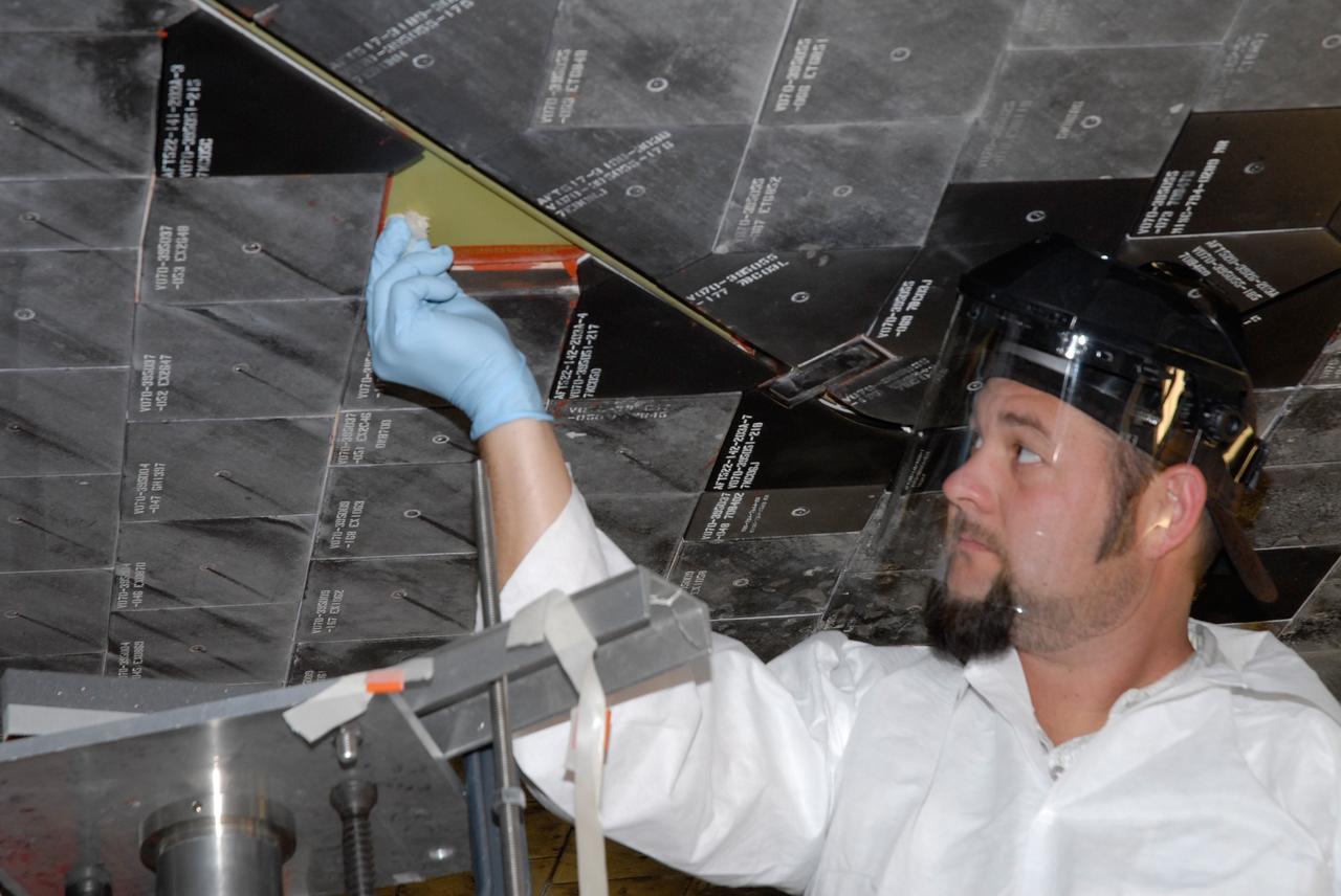 CAPE CANAVERAL, Fla. – Inside Orbiter Processing Facility 2 at NASA's Kennedy Space Center, a United Space Alliance technician installs Boeing Replacement Insulation 18, or BRI-18, tile on space shuttle Endeavour during processing activities. BRI-18 is the strongest material used for thermal insulation on the orbiters and, when coated to produce toughened unipiece fibrous insulation, provides a tile with extremely high-impact resistance. It is replacing other tiles on areas of the vehicle where impact risk is high, such as the landing gear doors, the wing leading edge and the external tank doors. Endeavour will deliver a multi-purpose logistics module to the International Space Station on its STS-126 mission. Launch is targeted for Nov. 10.  Photo credit: NASA/Jack Pfaller