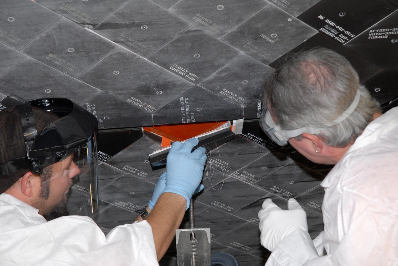 CAPE CANAVERAL, Fla. – Inside Orbiter Processing Facility 2 at NASA's Kennedy Space Center, United Space Alliance technicians install Boeing Replacement Insulation 18, or BRI-18, tile on space shuttle Endeavour during processing activities. BRI-18 is the strongest material used for thermal insulation on the orbiters and, when coated to produce toughened unipiece fibrous insulation, provides a tile with extremely high-impact resistance. It is replacing other tiles on areas of the vehicle where impact risk is high, such as the landing gear doors, the wing leading edge and the external tank doors. Endeavour will deliver a multi-purpose logistics module to the International Space Station on its STS-126 mission. Launch is targeted for Nov. 10.  Photo credit: NASA/Jack Pfaller