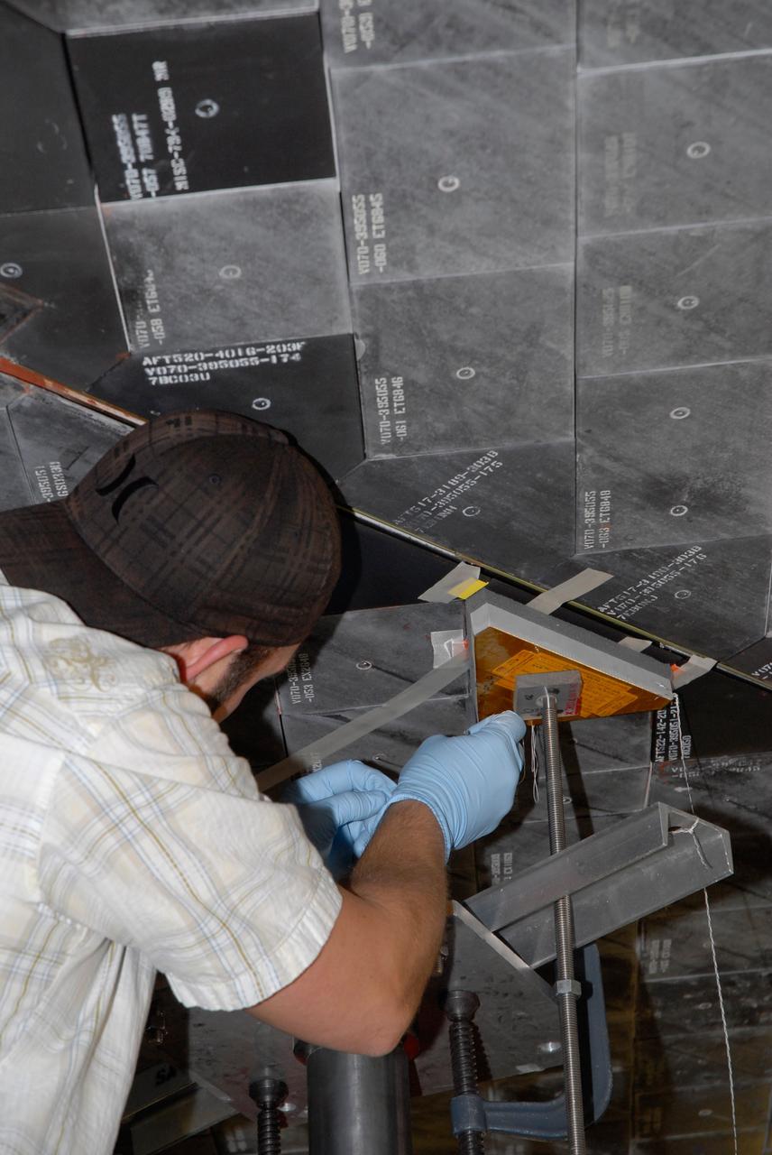 CAPE CANAVERAL, Fla. – Inside Orbiter Processing Facility 2 at NASA's Kennedy Space Center, a United Space Alliance technician installs Boeing Replacement Insulation 18, or BRI-18, tile on space shuttle Endeavour during processing activities. BRI-18 is the strongest material used for thermal insulation on the orbiters and, when coated to produce toughened unipiece fibrous insulation, provides a tile with extremely high-impact resistance. It is replacing other tiles on areas of the vehicle where impact risk is high, such as the landing gear doors, the wing leading edge and the external tank doors. Endeavour will deliver a multi-purpose logistics module to the International Space Station on its STS-126 mission. Launch is targeted for Nov. 10.  Photo credit: NASA/Jack Pfaller