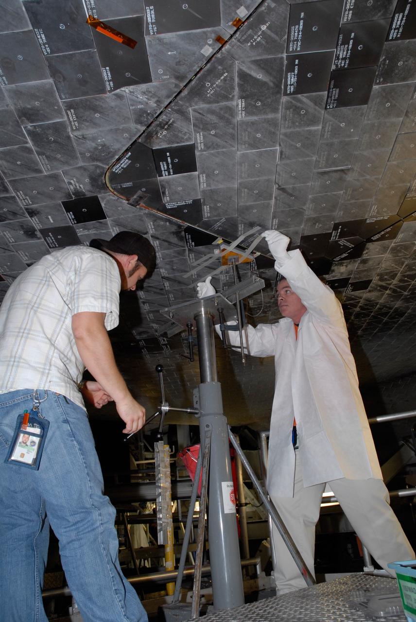 CAPE CANAVERAL, Fla. – Inside Orbiter Processing Facility 2 at NASA's Kennedy Space Center, United Space Alliance technicians install Boeing Replacement Insulation 18, or BRI-18, tile on space shuttle Endeavour during processing activities. BRI-18 is the strongest material used for thermal insulation on the orbiters and, when coated to produce toughened unipiece fibrous insulation, provides a tile with extremely high-impact resistance. It is replacing other tiles on areas of the vehicle where impact risk is high, such as the landing gear doors, the wing leading edge and the external tank doors. Endeavour will deliver a multi-purpose logistics module to the International Space Station on its STS-126 mission. Launch is targeted for Nov. 10.  Photo credit: NASA/Jack Pfaller