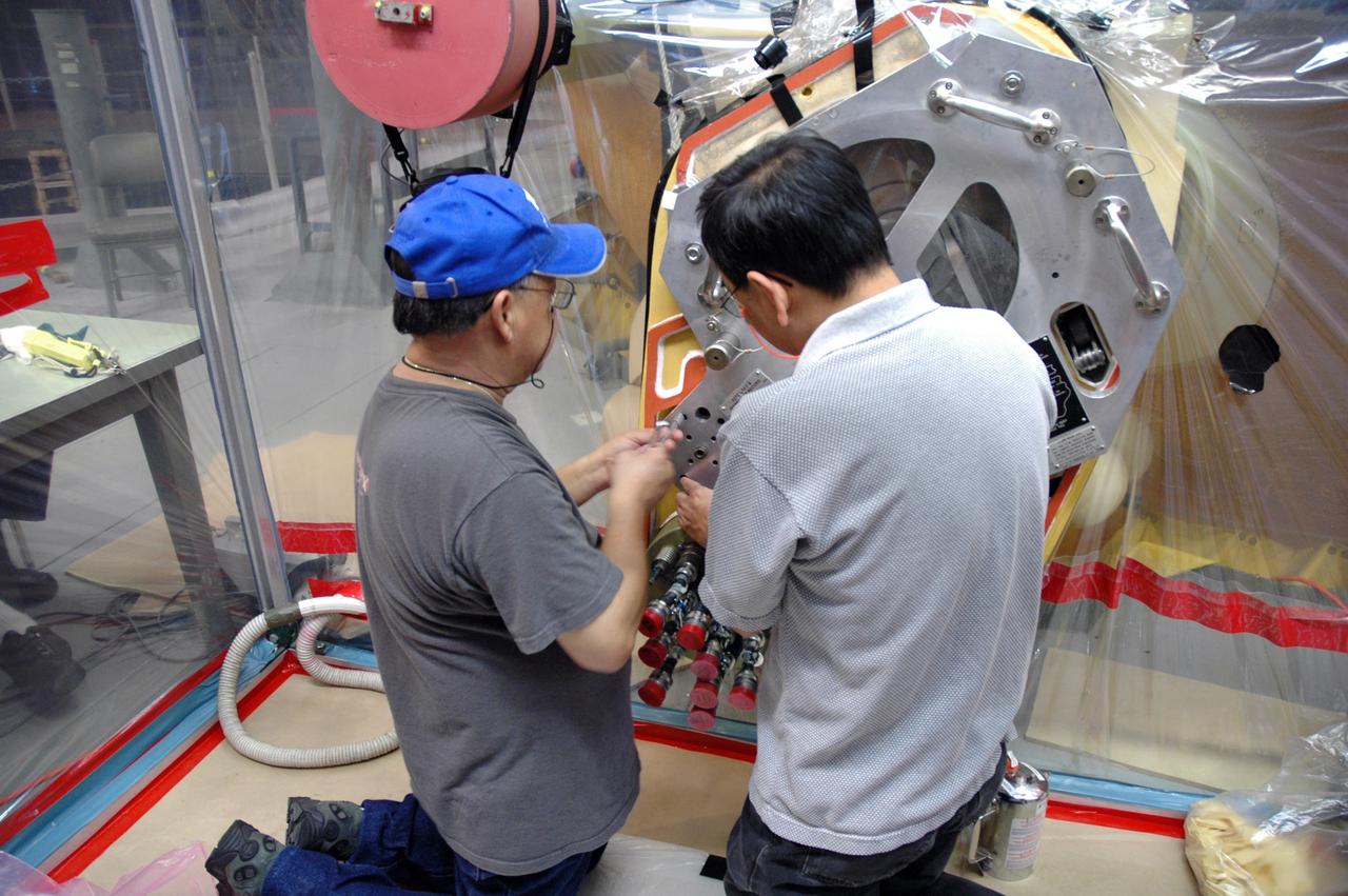 CAPE CANAVERAL, Fla. – Inside the Vehicle Assembly Building at NASA’s Kennedy Space Center, technicians install a plate cover over the quick disconnect system on Atlantis’ external tank. A valve was removed and replaced after small dings were found on the sealing surface of the quick disconnect system that handles liquid-hydrogen fuel for the shuttle’s three main engines. The tank will be attached to the twin solid rocket boosters on Aug. 3 for the STS-125 mission, the fifth and final shuttle servicing mission to NASA’s Hubble Space Telescope. During the mission, the crew will install new instruments on the telescope, including the Cosmic Origins Spectrograph and the Wide Field Camera 3. A refurbished Fine Guidance Sensor will replace one unit of three now onboard. Mission specialists will also install new gyroscopes, batteries and thermal blankets on the telescope. Launch is targeted for Oct. 8. Photo credit: NASA/Jim Grossmann