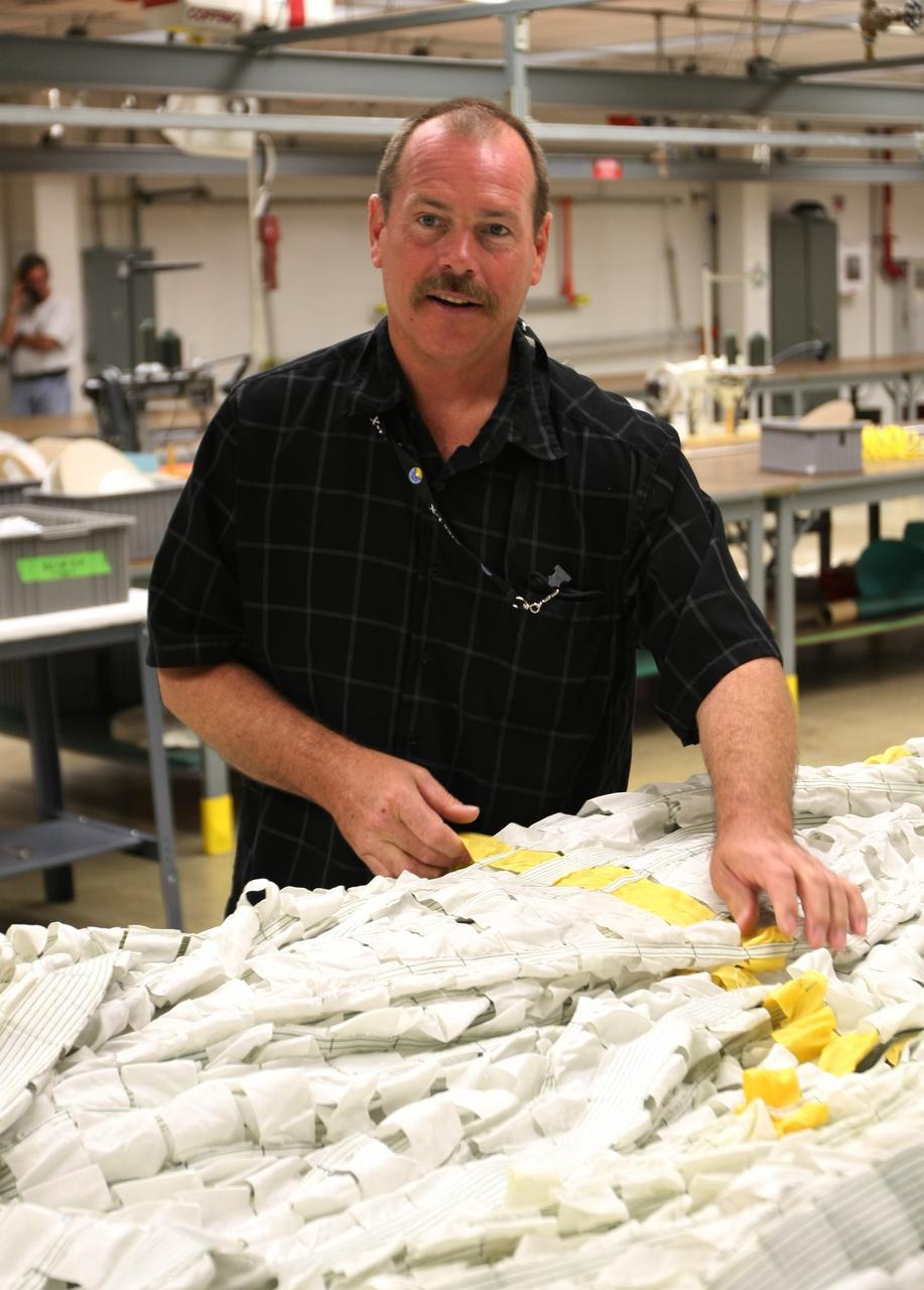 CAPE CANAVERAL, Fla. – In the Parachute Refurbishment Facility at NASA's Kennedy Space Center, Dave Hillebrandt checks strapping on an Ares-I parachute. Ares I is an in-line, two-stage rocket that will transport the Orion crew exploration vehicle to low-Earth orbit. The Ares I first stage will be a five-segment solid rocket booster based on the four-segment design used for the shuttle. As with the shuttle, this booster will fall away when spent, lowered by parachute into the Atlantic Ocean where it can be retrieved for re-use. Photo credit: NASA/Dimitri Gerondidakis
