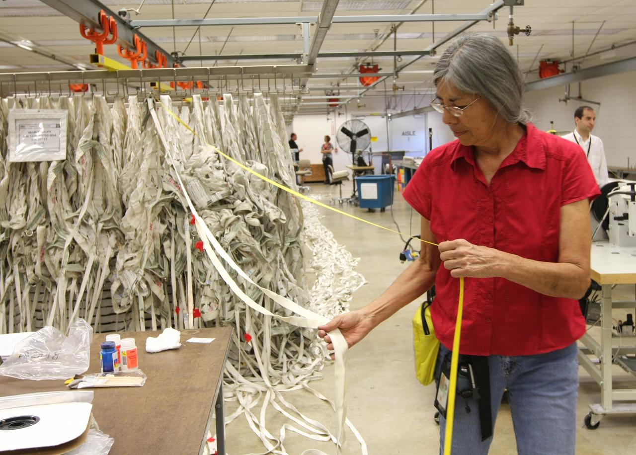 CAPE CANAVERAL, Fla. – In the Parachute Refurbishment Facility at NASA's Kennedy Space Center, Deborah Coombs, senior parachute technician, measures suspension lines for the Ares-I main canopy. Ares I is an in-line, two-stage rocket that will transport the Orion crew exploration vehicle to low-Earth orbit. The Ares I first stage will be a five-segment solid rocket booster based on the four-segment design used for the shuttle. As with the shuttle, this booster will fall away when spent, lowered by parachute into the Atlantic Ocean where it can be retrieved for re-use. Photo credit: NASA/Dimitri Gerondidakis