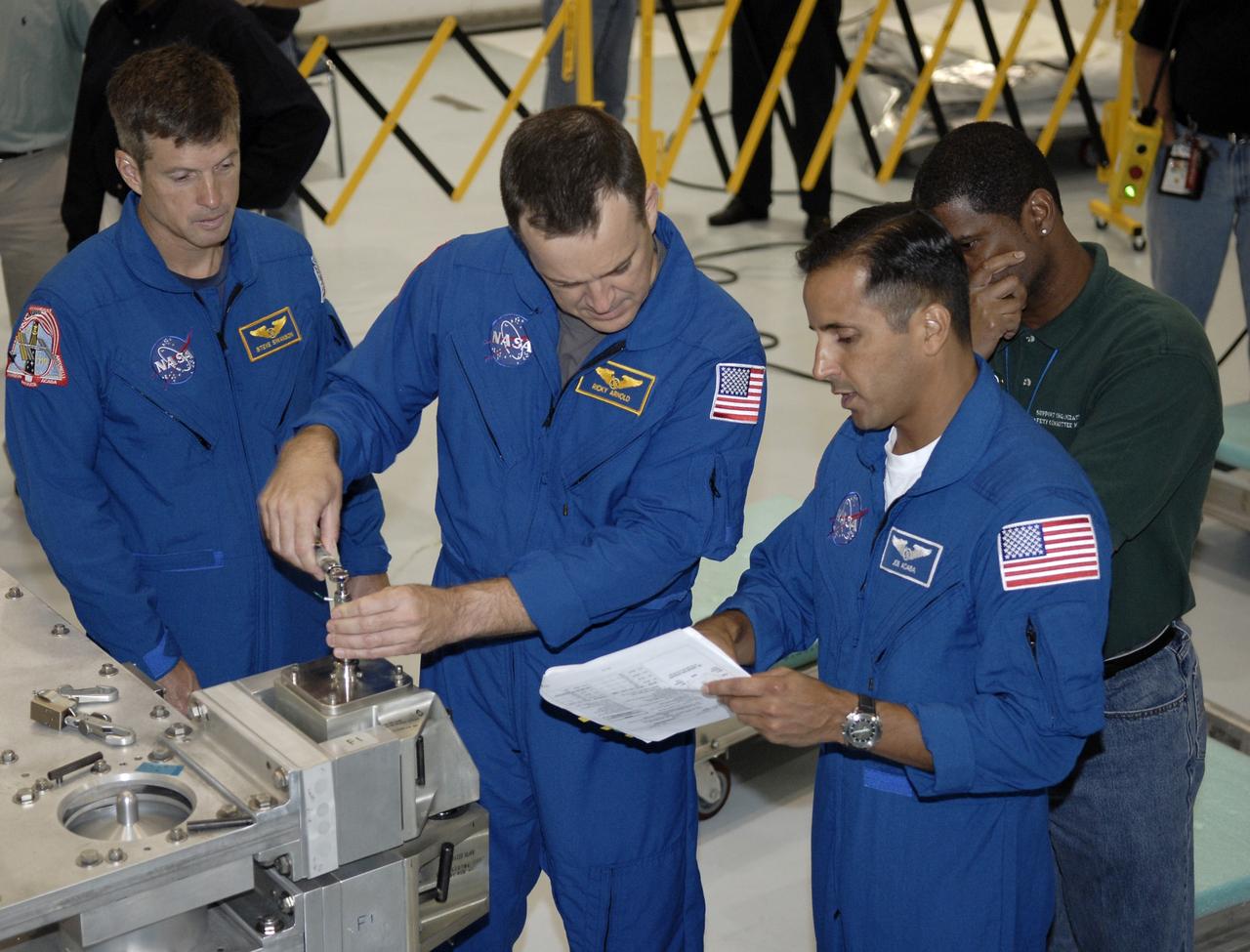 CAPE CANAVERAL, Fla. - In the Space Station Processing Facility at NASA's Kennedy Space Center, STS-119 Mission Specialist Richard Arnold, assisted by Mission Specialist Joseph Acaba at right, gets some hands-on training with hardware slated to fly on his upcoming space shuttle mission. Mission Specialist Steve Swanson observes at left.  On the STS-119 mission, space shuttle Discovery will carry the S6 truss segment to complete the 361-foot-long backbone of the International Space Station. The truss includes the fourth pair of solar array wings and electronics that convert sunlight to power for the orbiting laboratory. Launch is targeted for Feb. 12, 2009. Photo credit: NASA/Kim Shiflett