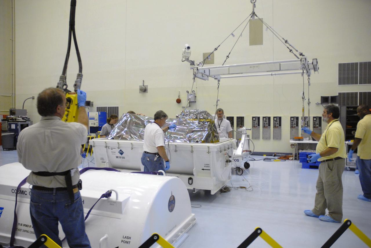 CAPE CANAVERAL, Fla. – In the airlock of the Payload Hazardous Servicing Facility at NASA's Kennedy Space Center, workers from NASA's Goddard Space Flight Center examine the Cosmic Origins Spectrograph, or COS, after the top from its transportation canister is removed.  The COS will be installed on the Hubble Space Telescope on space shuttle Atlantis' STS-125 mission.  COS will be the most sensitive ultraviolet spectrograph ever flown on Hubble and will probe the "cosmic web" - the large-scale structure of the universe whose form is determined by the gravity of dark matter and is traced by galaxies and intergalactic gas.  COS's far-ultraviolet channel has a sensitivity 30 times greater than that of previous spectroscopic instruments for the detection of extremely low light levels.  Launch of STS-125 is targeted for Oct. 8.  Photo credit: NASA/Jack Pfaller