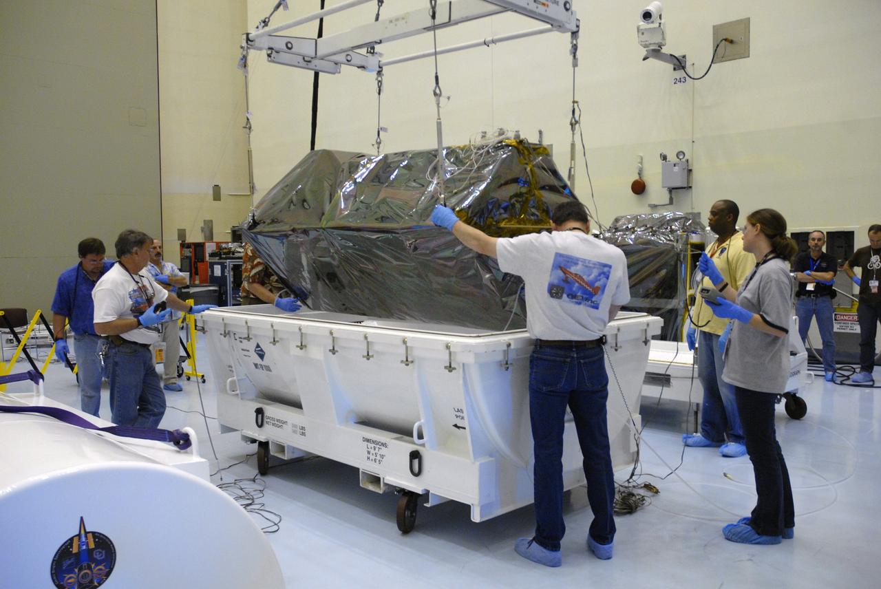CAPE CANAVERAL, Fla. – In the airlock of the Payload Hazardous Servicing Facility at NASA's Kennedy Space Center, workers from NASA's Goddard Space Flight Center prepare to lift the Cosmic Origins Spectrograph, or COS, from its transportation canister.  The COS will be installed on the Hubble Space Telescope on space shuttle Atlantis' STS-125 mission.  COS will be the most sensitive ultraviolet spectrograph ever flown on Hubble and will probe the "cosmic web" - the large-scale structure of the universe whose form is determined by the gravity of dark matter and is traced by galaxies and intergalactic gas.  COS's far-ultraviolet channel has a sensitivity 30 times greater than that of previous spectroscopic instruments for the detection of extremely low light levels.  Launch of STS-125 is targeted for Oct. 8.  Photo credit: NASA/Jack Pfaller