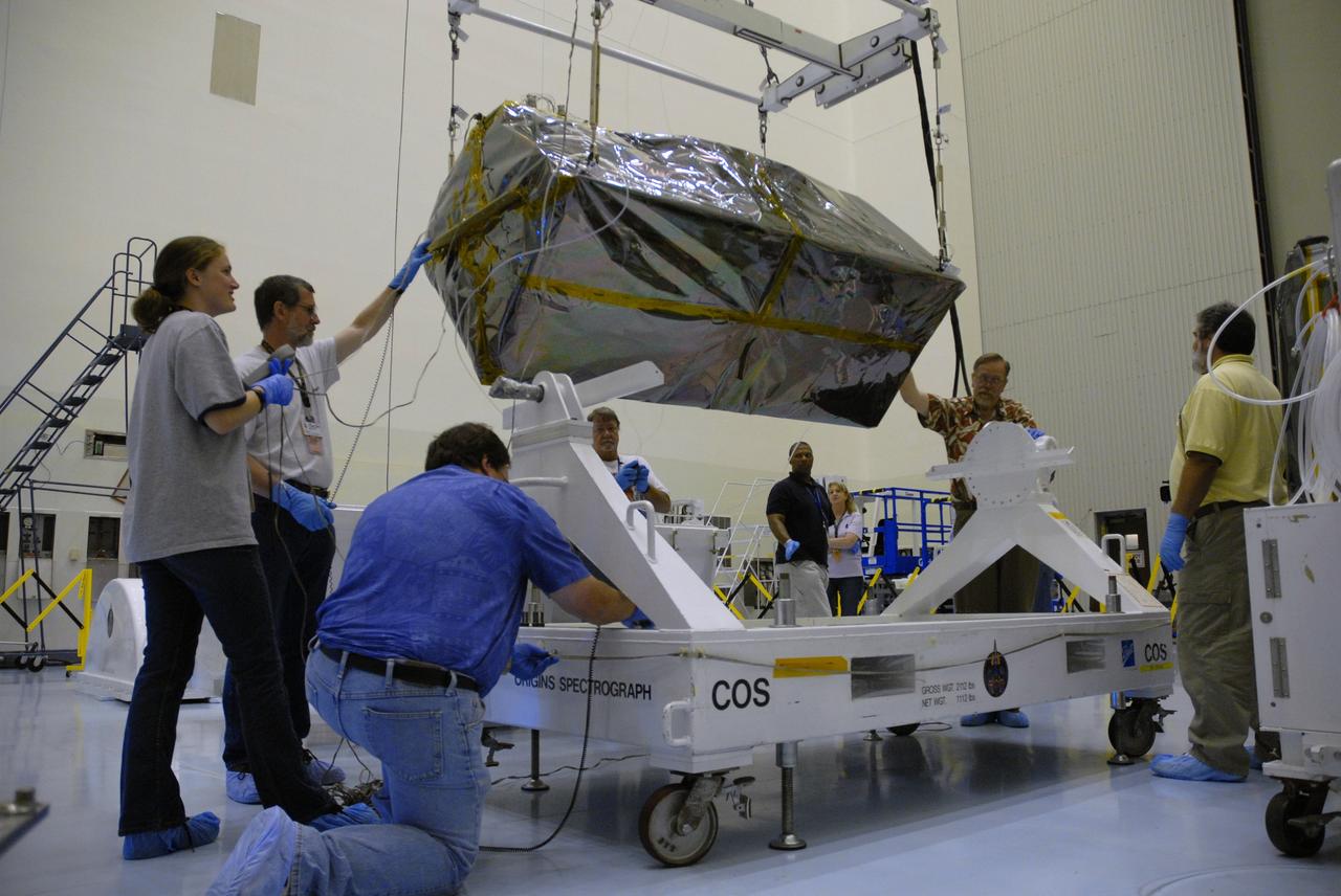CAPE CANAVERAL, Fla. – In the airlock of the Payload Hazardous Servicing Facility at NASA's Kennedy Space Center, workers from NASA's Goddard Space Flight Center lift the Cosmic Origins Spectrograph, or COS, from its transportation canister onto a dolly for its move into the clean room.  The COS will be installed on the Hubble Space Telescope on space shuttle Atlantis' STS-125 mission.  COS will be the most sensitive ultraviolet spectrograph ever flown on Hubble and will probe the "cosmic web" - the large-scale structure of the universe whose form is determined by the gravity of dark matter and is traced by galaxies and intergalactic gas.  COS's far-ultraviolet channel has a sensitivity 30 times greater than that of previous spectroscopic instruments for the detection of extremely low light levels.  Launch of STS-125 is targeted for Oct. 8.  Photo credit: NASA/Jack Pfaller