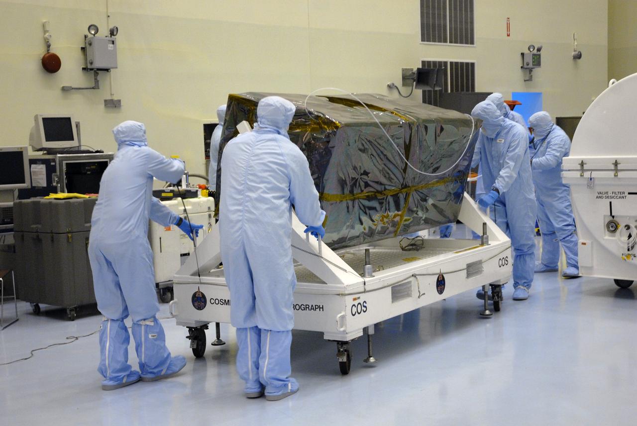 CAPE CANAVERAL, Fla. – At NASA's Kennedy Space Center, workers from NASA's Goddard Space Flight Center roll the Cosmic Origins Spectrograph, or COS, from the airlock, where it was removed from the shipping container, to the clean room of the Payload Hazardous Servicing Facility. The COS will be installed on the Hubble Space Telescope on space shuttle Atlantis' STS-125 mission.  COS will be the most sensitive ultraviolet spectrograph ever flown on Hubble and will probe the "cosmic web" - the large-scale structure of the universe whose form is determined by the gravity of dark matter and is traced by galaxies and intergalactic gas.  COS's far-ultraviolet channel has a sensitivity 30 times greater than that of previous spectroscopic instruments for the detection of extremely low light levels.  Launch of STS-125 is targeted for Oct. 8.  Photo credit: NASA/Jack Pfaller