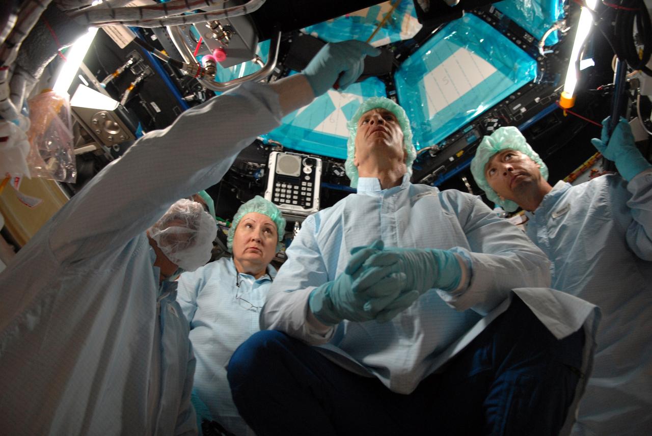 CAPE CANAVERAL, Fla. – In the Space Station Processing Facility at NASA's Kennedy Space Center, astronaut Charles Hobaugh, hands folded, conducts a fit check of the robotic workstation, or RWS, in the International Space Station's Cupola module.  From left, he is assisted by Boeing technician Terry Camarata, vehicle integration test engineer Louise Kleba of Flight Crew Operations, and engineer David Jackson, from Johnson Space Center.  The RWS is provided by the Canadian Space Agency.  The module was delivered by the European Space Agency in 2004 to Kennedy from Alenia Spazio in Turin, Italy.  Cupola will provide unprecedented views of activities outside the station and spectacular views of the Earth.  Crew members working inside the module will have a 360-degree panoramic view.  Cupola has the capability for command and control workstations to be installed to assist in space station remote manipulator system and extra vehicular activities.  Cupola is the final element of the space station core and is scheduled for launch on space shuttle Endeavour's STS-130 mission, targeted for Dec. 10, 2009.  Photo credit: NASA/Cory Huston