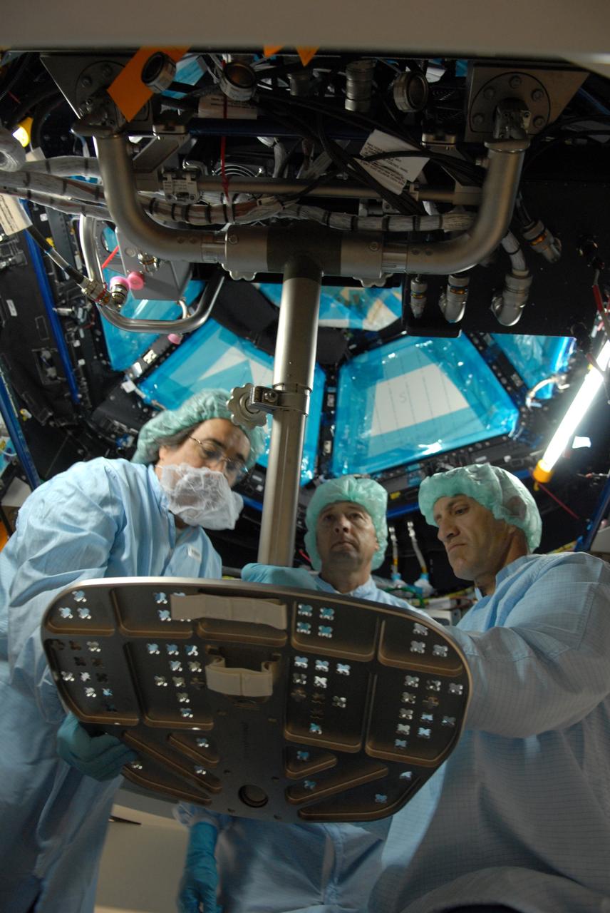 CAPE CANAVERAL, Fla. – In the Space Station Processing Facility at NASA's Kennedy Space Center, astronaut Charles Hobaugh, right, conducts a fit check of the robotic workstation, or RWS, in the International Space Station's Cupola module.  He is assisted by Boeing technician Terry Camarata, left, and engineer David Jackson, from Johnson Space Center. The RWS is provided by the Canadian Space Agency.  The module was delivered by the European Space Agency in 2004 to Kennedy from Alenia Spazio in Turin, Italy.  Cupola will provide unprecedented views of activities outside the station and spectacular views of the Earth.  Crew members working inside the module will have a 360-degree panoramic view.  Cupola has the capability for command and control workstations to be installed to assist in space station remote manipulator system and extra vehicular activities.  Cupola is the final element of the space station core and is scheduled for launch on space shuttle Endeavour's STS-130 mission, targeted for Dec. 10, 2009.  Photo credit: NASA/Cory Huston