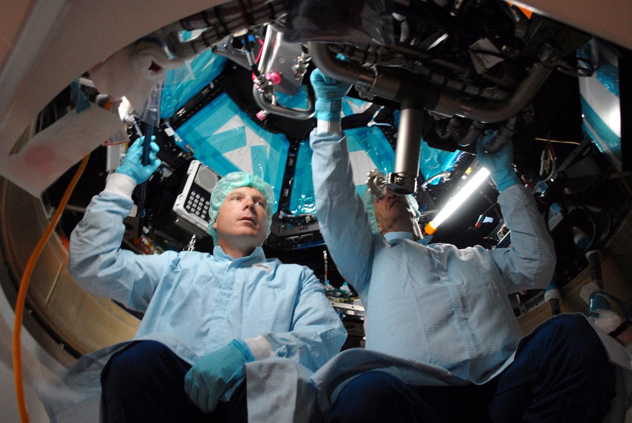 CAPE CANAVERAL, Fla. – In the Space Station Processing Facility at NASA's Kennedy Space Center, astronauts Terry Virts, left, and Charles Hobaugh familiarize themselves with the operation of the robotic workstation, or RWS, in the International Space Station's Cupola module.  The RWS is provided by the Canadian Space Agency.  The module was delivered by the European Space Agency in 2004 to Kennedy from Alenia Spazio in Turin, Italy.  Cupola will provide unprecedented views of activities outside the station and spectacular views of the Earth.  Crew members working inside the module will have a 360-degree panoramic view.  Cupola has the capability for command and control workstations to be installed to assist in space station remote manipulator system and extra vehicular activities.  Cupola is the final element of the space station core and is scheduled for launch on space shuttle Endeavour's STS-130 mission, targeted for Dec. 10, 2009.  Photo credit: NASA/Cory Huston