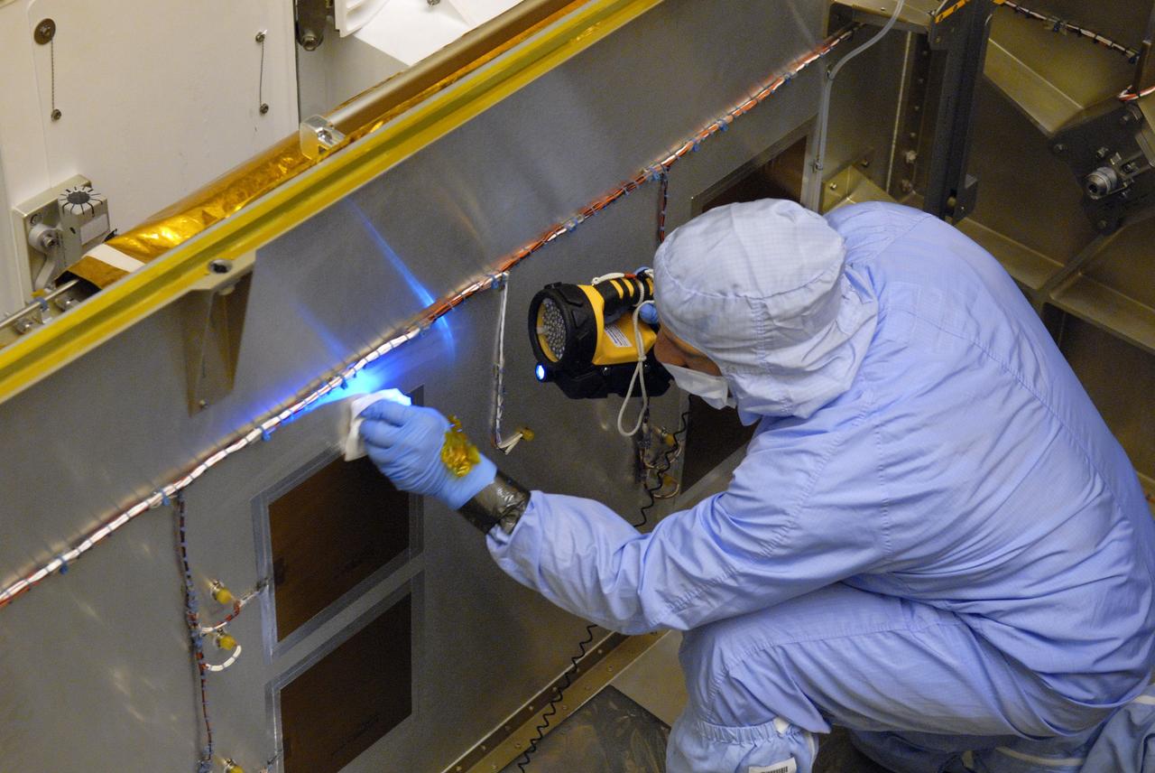 CAPE CANAVERAL, Fla. – In the clean room of the Payload Hazardous Processing Facility at NASA's Kennedy Space Center, workers from NASA's Goddard Space Flight Center use black light inspection for a thorough cleaning of the protective carrier for the Cosmic Origins Spectrograph, or COS. Black light inspection uses UVA fluorescence to detect possible particulate microcontamination, minute cracks or fluid leaks. The COS will be installed on the Hubble Space Telescope on space shuttle Atlantis' STS-125 mission. COS will be the most sensitive ultraviolet spectrograph ever flown on Hubble and will probe the "cosmic web" - the large-scale structure of the universe whose form is determined by the gravity of dark matter and is traced by galaxies and intergalactic gas. The COS far-ultraviolet channel has a sensitivity 30 times greater than that of previous spectroscopic instruments for the detection of extremely low light levels. Launch of Atlantis on the STS-125 mission is targeted for Oct. 8. Photo credit: NASA/Kim Shiflett