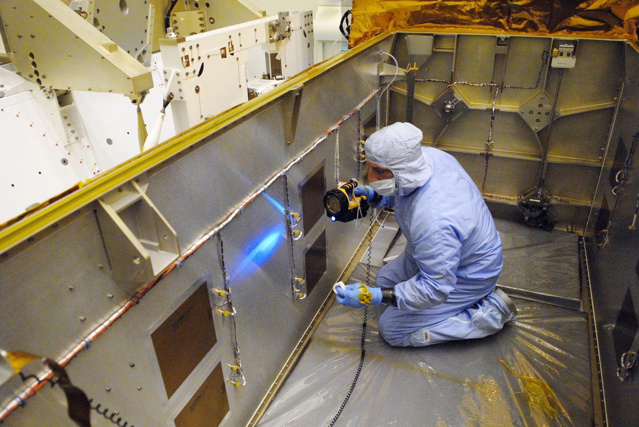 CAPE CANAVERAL, Fla. – In the clean room of the Payload Hazardous Processing Facility at NASA's Kennedy Space Center, workers from NASA's Goddard Space Flight Center use black light inspection for a thorough cleaning of the protective carrier for the Cosmic Origins Spectrograph, or COS. Black light inspection uses UVA fluorescence to detect possible particulate microcontamination, minute cracks or fluid leaks. The COS will be installed on the Hubble Space Telescope on space shuttle Atlantis' STS-125 mission. COS will be the most sensitive ultraviolet spectrograph ever flown on Hubble and will probe the "cosmic web" - the large-scale structure of the universe whose form is determined by the gravity of dark matter and is traced by galaxies and intergalactic gas. The COS far-ultraviolet channel has a sensitivity 30 times greater than that of previous spectroscopic instruments for the detection of extremely low light levels. Launch of Atlantis on the STS-125 mission is targeted for Oct. 8. Photo credit: NASA/Kim Shiflett