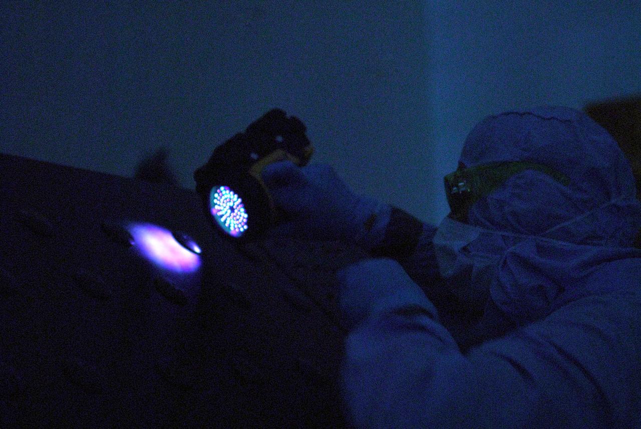 CAPE CANAVERAL, Fla. –In the clean room of the Payload Hazardous Processing Facility at NASA's Kennedy Space Center, a worker from NASA's Goddard Space Flight Center uses black light inspection for a thorough cleaning of the Cosmic Origins Spectrograph, or COS.  Black light inspection uses UVA fluorescence to detect possible particulate microcontamination, minute cracks or fluid leaks. The COS will be installed on the Hubble Space Telescope on space shuttle Atlantis' STS-125 mission. COS will be the most sensitive ultraviolet spectrograph ever flown on Hubble and will probe the "cosmic web" - the large-scale structure of the universe whose form is determined by the gravity of dark matter and is traced by galaxies and intergalactic gas. The COS far-ultraviolet channel has a sensitivity 30 times greater than that of previous spectroscopic instruments for the detection of extremely low light levels. Launch of Atlantis on the STS-125 mission is targeted for Oct. 8. Photo credit: NASA/Kim Shiflett