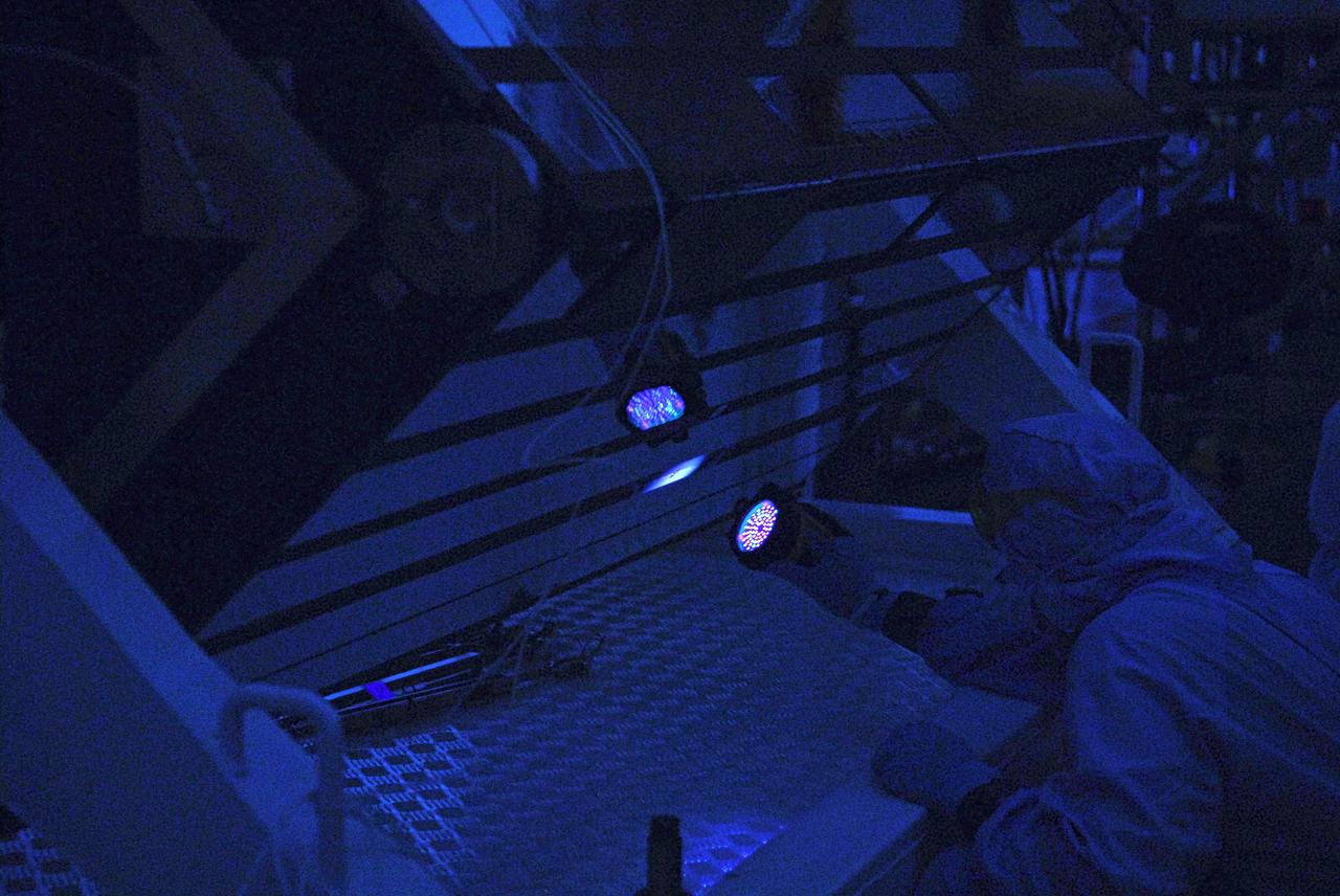 CAPE CANAVERAL, Fla. – In the clean room of the Payload Hazardous Processing Facility at NASA's Kennedy Space Center, a worker from NASA's Goddard Space Flight Center uses black light inspection for a thorough cleaning of the Cosmic Origins Spectrograph, or COS.  Black light inspection uses UVA fluorescence to detect possible particulate microcontamination, minute cracks or fluid leaks. The COS will be installed on the Hubble Space Telescope on space shuttle Atlantis' STS-125 mission. COS will be the most sensitive ultraviolet spectrograph ever flown on Hubble and will probe the "cosmic web" - the large-scale structure of the universe whose form is determined by the gravity of dark matter and is traced by galaxies and intergalactic gas. The COS far-ultraviolet channel has a sensitivity 30 times greater than that of previous spectroscopic instruments for the detection of extremely low light levels. Launch of Atlantis on the STS-125 mission is targeted for Oct. 8. Photo credit: NASA/Kim Shiflett