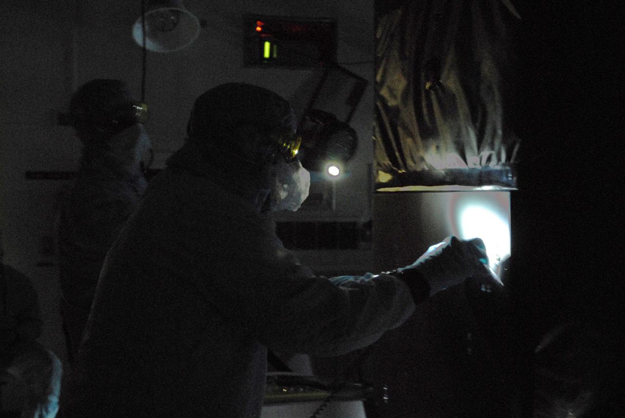 CAPE CANAVERAL, Fla. –   Technicians in the Payload Hazardous Servicing Facility at NASA's Kennedy Space Center perform backlight inspection and cleaning  on the Fine Guidance Sensor, or FGS.  The FGS is part of the payload for the fifth and final Hubble servicing mission, STS-125, aboard space shuttle Atlantis. Black light inspection uses UVA fluorescence to detect possible particulate microcontamination, minute cracks or fluid leaks. An FGS consists of a large structure housing a collection of mirrors, lenses, servos, prisms, beam splitters and photomultiplier tubes. There are three fine guidance sensors on Hubble located at 90-degree intervals around the circumference of the telescope. Along with the gyroscopes, the optical sensors are a key component of Hubble’s highly complex but extraordinarily effective “pointing control system.”  Atlantis is targeted to launch Oct. 8. Photo credit: NASA/Jack Pfaller
