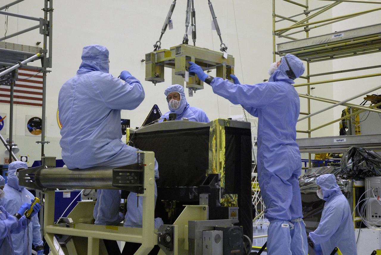 CAPE CANAVERAL, Fla. –  Technicians in the Payload Hazardous Servicing Facility at NASA's Kennedy Space Center help guide a specialized overhead crane toward the Fine Guidance Sensor, or FGS. The sensor will be lifted and moved to the Orbital Replacement Unit Carrier or ORUC, for installation. An FGS consists of a large structure housing a collection of mirrors, lenses, servos, prisms, beam splitters and photomultiplier tubes. There are three fine guidance sensors on Hubble located at 90-degree intervals around the circumference of the telescope. Along with the gyroscopes, the optical sensors are a key component of Hubble’s highly complex but extraordinarily effective “pointing control system.”  The ORUC is one of three carriers that are being prepared for the integration of telescope science instruments, both internal and external replacement components, as well as the flight support equipment to be used by the astronauts during the fifth and final Hubble servicing mission, STS-125, on space shuttle Atlantis.  Launch is targeted for Oct. 8. Photo credit: NASA/Jim Grossmann