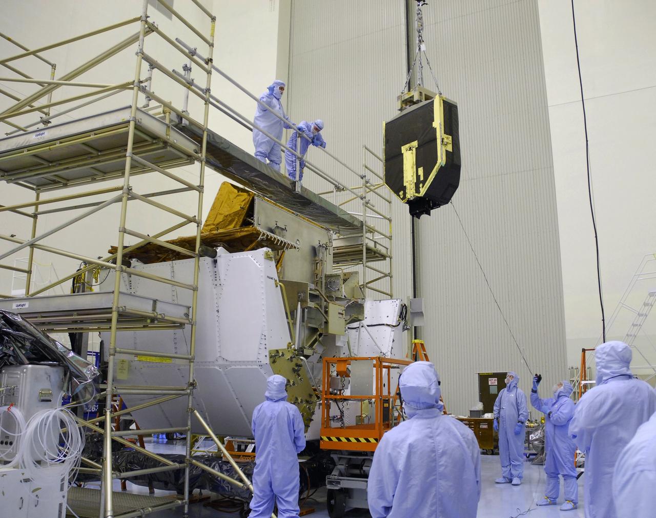 CAPE CANAVERAL, Fla. – Technicians in the Payload Hazardous Servicing Facility at NASA's Kennedy Space Center help guide the Fine Guidance Sensor, or FGS, as it is lifted over the crossbar of the stand at right. The sensor will be installed on the Orbital Replacement Unit Carrier or ORUC, below. An FGS consists of a large structure housing a collection of mirrors, lenses, servos, prisms, beam splitters and photomultiplier tubes. There are three fine guidance sensors on Hubble located at 90-degree intervals around the circumference of the telescope. Along with the gyroscopes, the optical sensors are a key component of Hubble’s highly complex but extraordinarily effective “pointing control system.” The ORUC is one of three carriers that are being prepared for the integration of telescope science instruments, both internal and external replacement components, as well as the flight support equipment to be used by the astronauts during the fifth and final Hubble servicing mission, STS-125, on space shuttle Atlantis. Launch is targeted for Oct. 8. Photo credit: NASA/Jim Grossmann