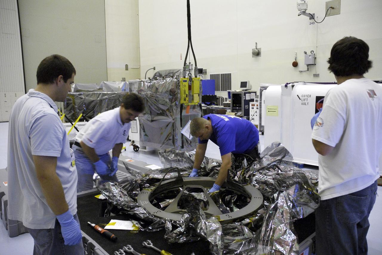 CAPE CANAVERAL, Fla. – In the Payload Hazardous Servicing Facility at NASA's Kennedy Space Center, technicians attach cables to lift the Soft Capture and Rendezvous System, or SCRS. The SCRS will enable the future rendezvous, capture and safe disposal of Hubble by either a crewed or robotic mission. The ring-like device attaches to Hubble’s aft bulkhead. The SCRS greatly increases the current shuttle capture interfaces on Hubble, therefore significantly reducing the rendezvous and capture design complexities associated with the disposal mission. The SCRS comprises the Soft Capture Mechanism system and the Relative Navigation System and is part of the payload on the fifth and final Hubble servicing mission, STS-125, targeted for launch Oct. 8. Photo credit: NASA/Jack Pfaller