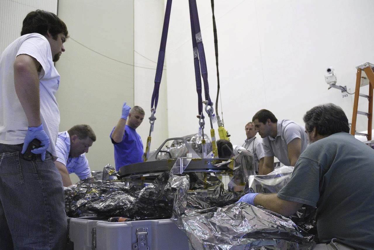 CAPE CANAVERAL, Fla. – In the Payload Hazardous Servicing Facility at NASA's Kennedy Space Center, technicians monitor the lifting of the Soft Capture Mechanism (SCM), part of the Soft Capture and Rendezvous System, or SCRS, from its shipping container. The SCRS will enable the future rendezvous, capture and safe disposal of Hubble by either a crewed or robotic mission. The ring-like device attaches to Hubble’s aft bulkhead. The SCRS greatly increases the current shuttle capture interfaces on Hubble, therefore significantly reducing the rendezvous and capture design complexities associated with the disposal mission. The SCRS comprises the Soft Capture Mechanism system and the Relative Navigation System and is part of the payload on the fifth and final Hubble servicing mission, STS-125, targeted for launch Oct. 8. Photo credit: NASA/Jack Pfaller