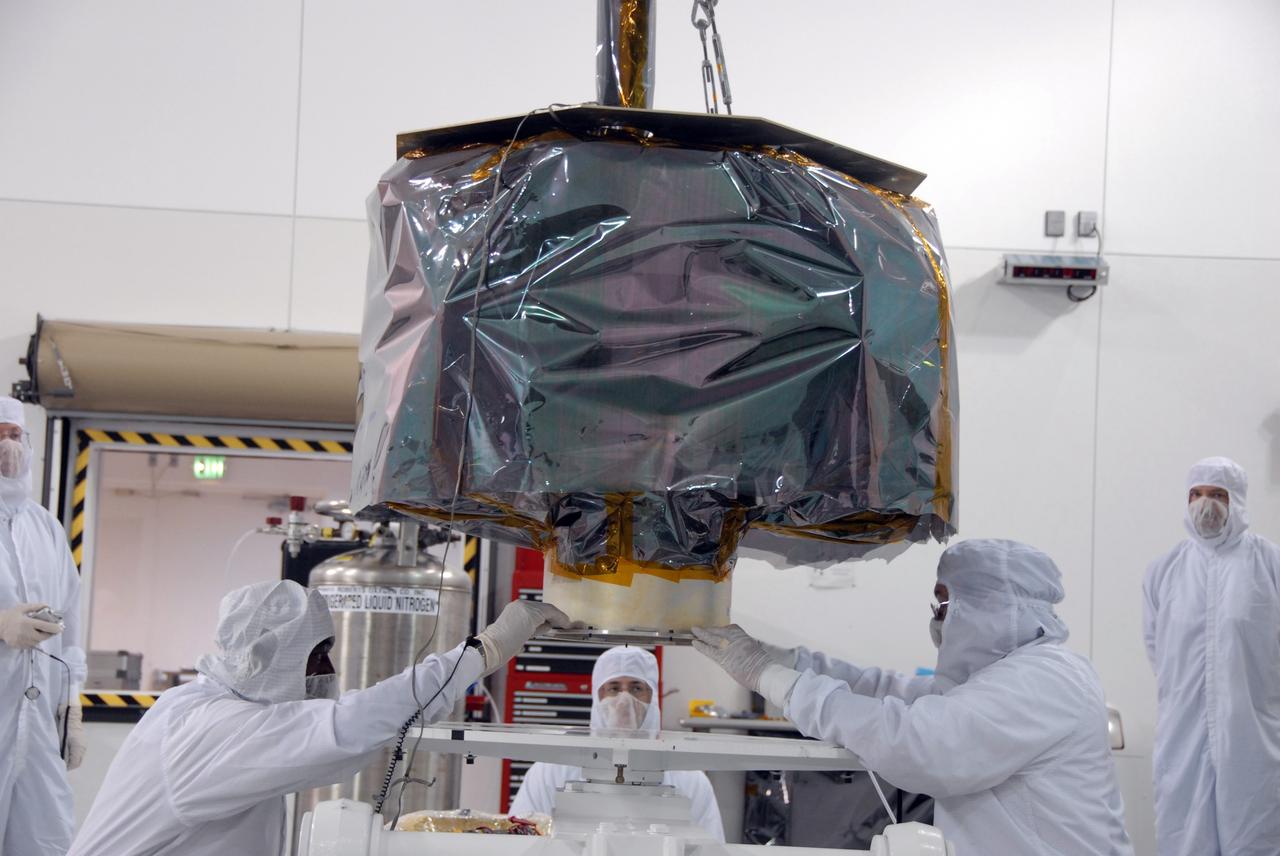 VANDENBERG AIR FORCE BASE, Calif. – At Vandenberg Air Force Base in California, technicians help guide NASA's Interstellar Boundary Explorer, or IBEX, mission spacecraft as an overhead crane lowers it into place on the mobile stand. The IBEX satellite will make the first map of the boundary between the Solar System and interstellar space. IBEX is the first mission designed to detect the edge of the Solar System. As the solar wind from the sun flows out beyond Pluto, it collides with the material between the stars, forming a shock front. IBEX contains two neutral atom imagers designed to detect particles from the termination shock at the boundary between the Solar System and interstellar space. IBEX also will study galactic cosmic rays, energetic particles from beyond the Solar System that pose a health and safety hazard for humans exploring beyond Earth orbit. IBEX will make these observations from a highly elliptical orbit that takes it beyond the interference of the Earth's magnetosphere. IBEX is targeted for launch from the Pegasus XL rocket on Oct. 5. Photo credit: NASA