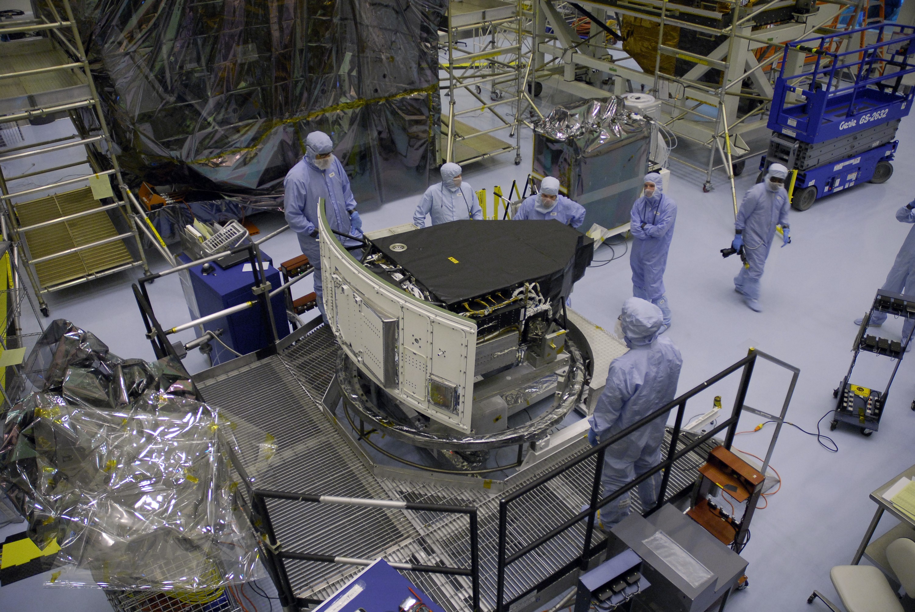 CAPE CANAVERAL, Fla. – In the Payload Hazardous Servicing Facility at NASA's Kennedy Space Center, technicians wait for the rotation of the Wide Field Camera 3, or WFC3, in order to attach a crane.  The WFC3 will be transferred to the Super Lightweight Interchangeable Carrier.  WFC3 is part of the payload on space shuttle Atlantis' STS-125 mission for the fifth and final Hubble servicing flight to NASA's Hubble Space Telescope. The curved edge shown at left is the radiator, the "outside" of WFC3 that will be exposed to space and will expel heat out of Hubble and into space through black body radiation.   As Hubble enters the last stage of its life, WFC3 will be Hubble's next evolutionary step, allowing Hubble to peer ever further into the mysteries of the cosmos. WFC3 will study a diverse range of objects and phenomena, from young and extremely distant galaxies, to much more nearby stellar systems, to objects within our very own solar system. WFC3 will take the place of Wide Field Planetary Camera 2, which astronauts will bring back to Earth aboard the shuttle. Launch of Atlantis is targeted at 1:34 a.m. EDT Oct. 8.  Photo credit: NASA/Amanda Diller