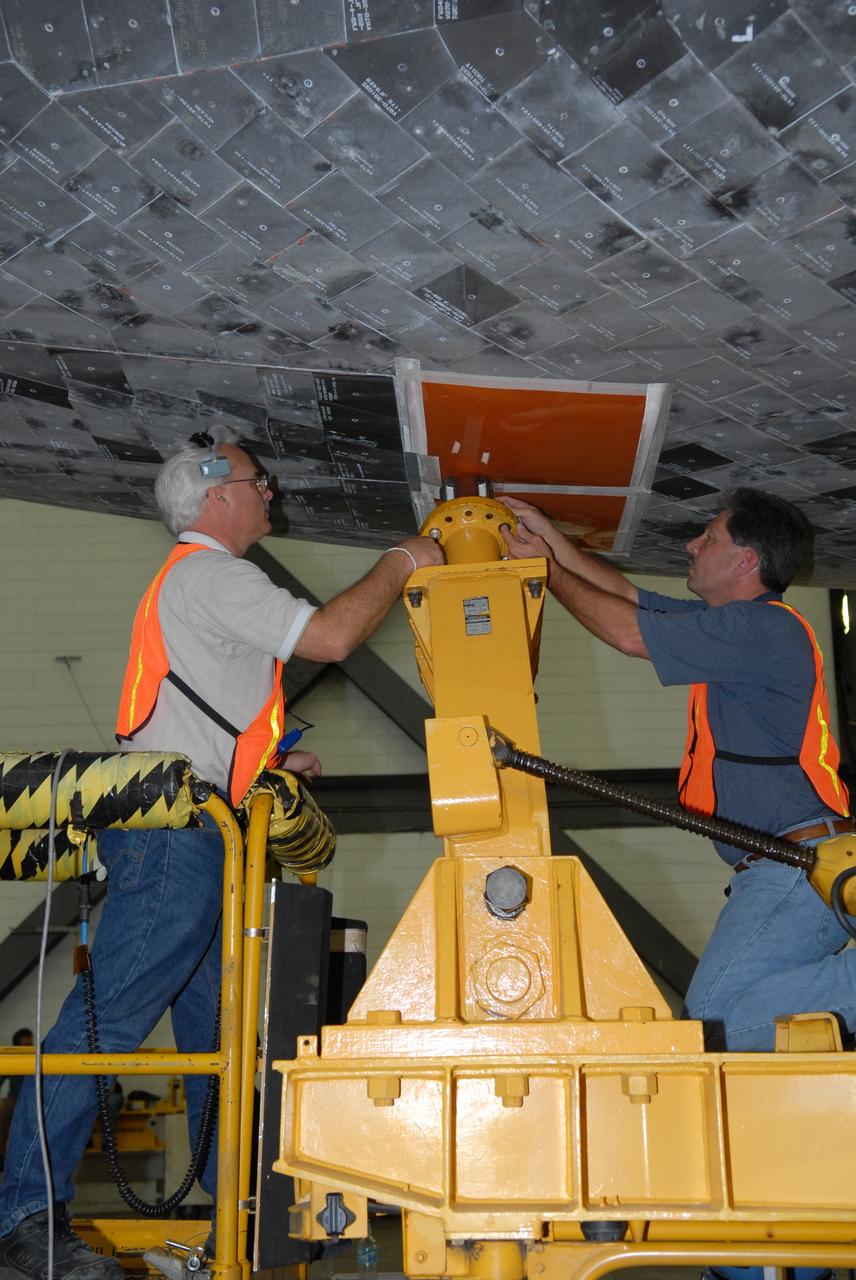 CAPE CANAVERAL, Fla. –   In the Vehicle Assembly Building transfer aisle at NASA's Kennedy Space Center, workers detach space shuttle Atlantis from its transporter.  An overhead crane will lift Atlantis to vertical for transfer to high bay 3 to be stacked with its external fuel tank and twin solid rocket boosters.  After additional preparations are made, the shuttle will be rolled out to Launch Pad 39A to prepare for launch on the STS-125 mission targeted for Oct. 8.   Photo credit: NASA/Jack Pfaller