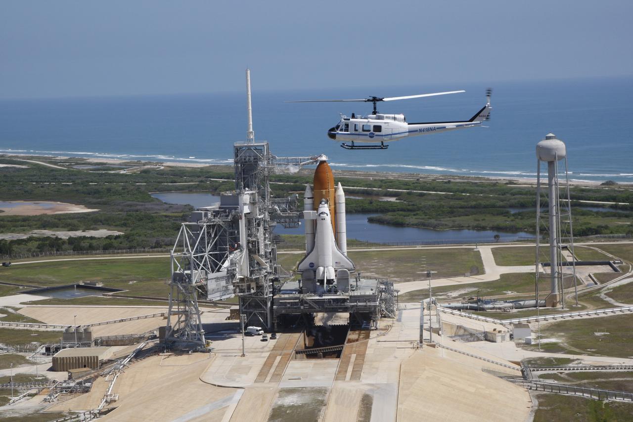 CAPE CANAVERAL, Fla. – A new NASA helicopter circles space shuttle Discovery on Launch Pad 39A prior to launch on the STS-124 mission. To the left of the shuttle is the fixed service structure with the 80-foot lightning mast on top. The rotating service structure, normally closed around the shuttle, is open for liftoff. At right of the pad is the 300,000-gallon water tower that provides the water used for sound suppression on the pad during liftoff. In the background is the Atlantic Ocean. Discovery is making its 35th flight. The STS-124 mission is the 26th in the assembly of the space station. It is the second of three flights launching components to complete the Japan Aerospace Exploration Agency's Kibo laboratory.