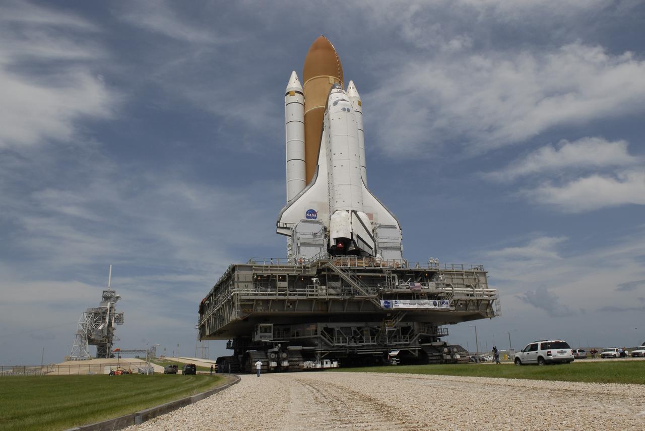 CAPE CANAVERAL, Fla. –  Space Space shuttle Atlantis curves toward Launch Pad 39A (at left) on the crawlerway at NASA's Kennedy Space Center after rolling from the Vehicle Assembly Building. The shuttle stack, with solid rocket boosters and external fuel tank attached to Atlantis, rest on the mobile launcher platform.  Movement is provided by the crawler-transporter underneath.  First motion occurred at 9:19 a.m. EDT. The Sept. 2 rollout date was postponed due to Tropical Storm Hanna’s shift to a northern track. Atlantis is scheduled to launch on the STS-125 mission to service NASA’s Hubble Space Telescope.  Launch is targeted for Oct. 8.  Photo credit: NASA/Kim Shiflett