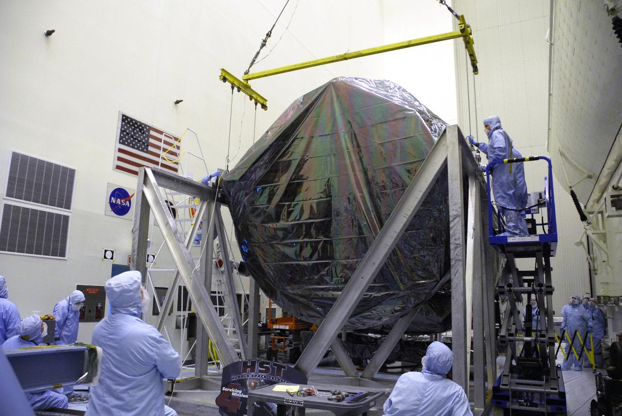 CAPE CANAVERAL, Fla. - In the Payload Hazardous Servicing Facility at NASA’s Kennedy Space Center, an overhead crane lifts the Flight Support System carrier with the Soft Capture Mechanism under protective cover. The carrier is one of four associated with the STS-125 mission to service the Hubble Space Telescope. It will be installed in the payload canister for transfer to Launch Pad 39A. At the pad, all the carriers will be loaded into space shuttle Atlantis’ payload bay. Launch of Atlantis is targeted for Oct. 10. Photo credit: NASA/Cory Huston