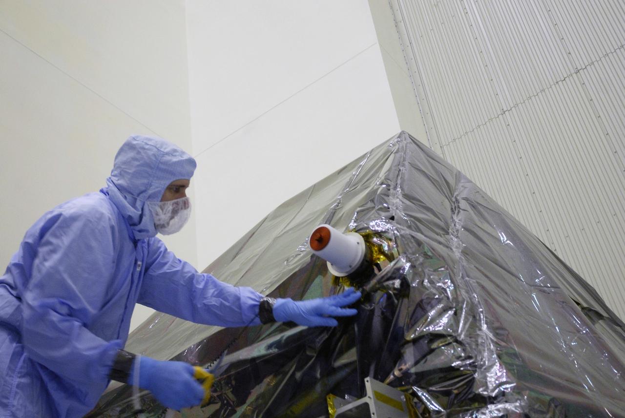 CAPE CANAVERAL, Fla. - In the Payload Hazardous Servicing Facility at NASA's Kennedy Space Center, a technician begins uncovering the Super Lightweight Interchangeable Carrier, or SLIC. Contamination discovered Sept. 17 during preparations to deliver NASA's Hubble Space Telescope servicing payload to Launch Pad 39A will be removed. Cleanliness is extremely important for space shuttle Atlantis’ STS-125 mission to Hubble, and the teams have insured that the SLIC is ready to fly. The SLIC, which holds battery module assemblies for servicing of the Hubble Space Telescope on the STS-125 mission, is built with state-of-the-art, lightweight, composite materials - carbon fiber with a cyanate ester resin and a titanium metal matrix composite. These composites have greater strength-to-mass ratios than the metals typically used in spacecraft design. The carrier is one of four being transferred to Launch Pad 39A. At the pad, the carriers will be loaded into Atlantis’ payload bay. Launch of Atlantis is targeted for Oct. 10. Photo credit: NASA/Jack Pfaller