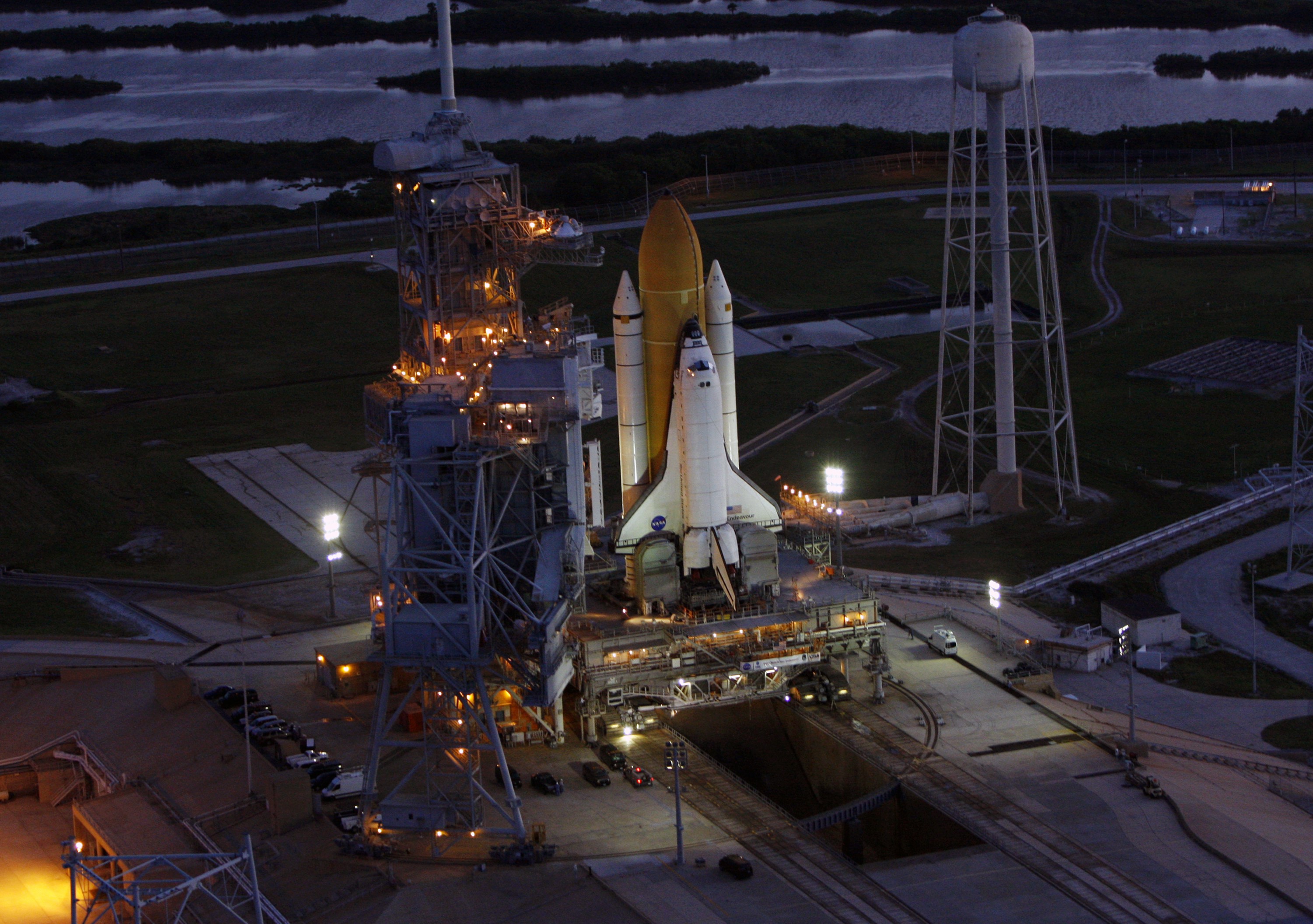 CAPE CANAVERAL, Fla. -  Space shuttle Endeavour on Launch Pad 39B is viewed from the air after the rollout from the Vehicle Assembly Building at NASA's Kennedy Space Center.  The shuttle and mobile launcher platform it sits on are atop the crawler-transporter. At right is the tower that holds 300,000 gallons of water used for sound suppression on the pad during liftoff. First motion out of the Vehicle Assembly Building was at 11:15 p.m. Sept. 18.  Endeavour completed the 4.2-mile journey at 6:59 a.m. EDT. For the first time since July 2001, two shuttles are on the launch pads at the same time at the center. Endeavour will stand by at pad B in the unlikely event that a rescue mission is necessary during space shuttle Atlantis' upcoming mission to repair NASA's Hubble Space Telescope, targeted to launch Oct. 10. After Endeavour is cleared from its duty as a rescue spacecraft, it will be moved to Launch Pad 39A for the STS-126 mission to the International Space Station. That flight is targeted for launch Nov. 12. Photo credit: NASA/Troy Cryder