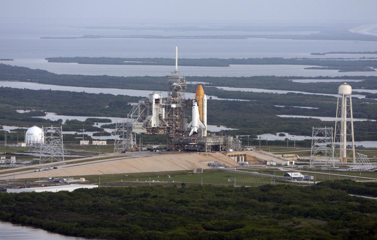 CAPE CANAVERAL, Fla. -  Space shuttle Endeavour on Launch Pad 39B is viewed from the air after the rollout from the Vehicle Assembly Building at NASA's Kennedy Space Center.  At left of the shuttle is the open rotating service structure and the fixed service structure with the 80-foot lightning mast on top. At right is the tower that holds 300,000 gallons of water used for sound suppression on the pad during liftoff. First motion out of the Vehicle Assembly Building was at 11:15 p.m. Sept. 18. In the background is the Banana River.  Endeavour completed the 4.2-mile journey at 6:59 a.m. EDT. For the first time since July 2001, two shuttles are on the launch pads at the same time at the center. Endeavour will stand by at pad B in the unlikely event that a rescue mission is necessary during space shuttle Atlantis' upcoming mission to repair NASA's Hubble Space Telescope, targeted to launch Oct. 10. After Endeavour is cleared from its duty as a rescue spacecraft, it will be moved to Launch Pad 39A for the STS-126 mission to the International Space Station. That flight is targeted for launch Nov. 12. Photo credit: NASA/Troy Cryder