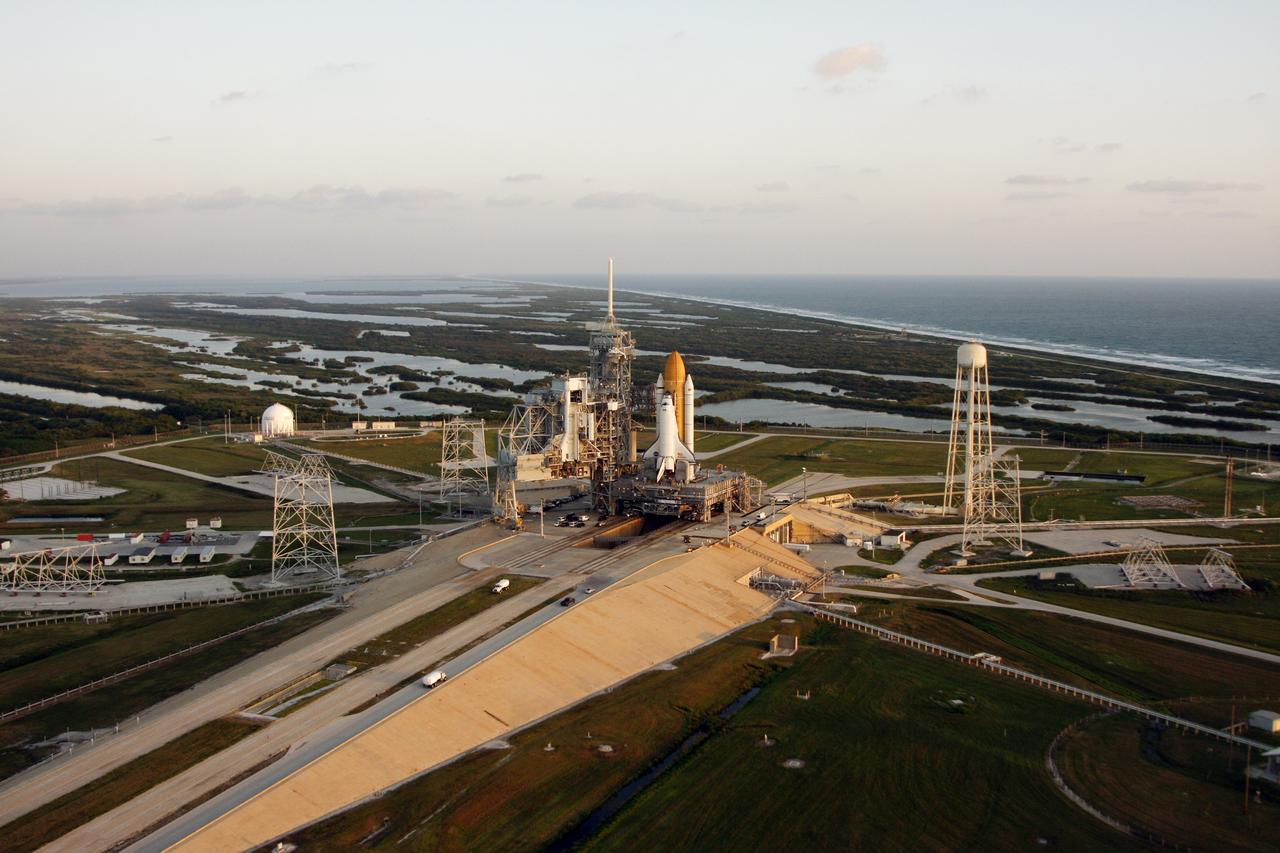 CAPE CANAVERAL, Fla. -   The aerial view of Launch Pad 39B at NASA's Kennedy Space Center shows the Atlantic Ocean at right, the Banana River near the pad, and space shuttle Endeavour after its rollout from the Vehicle Assembly Building.   At left of the shuttle is the open rotating service structure and the fixed service structure with the 80-foot lightning mast on top. At right is the tower that holds 300,000 gallons of water used for sound suppression on the pad during liftoff. First motion of Endeavour out of the VAB was at 11:15 p.m. Sept. 18.  Endeavour completed the 4.2-mile journey at 6:59 a.m. EDT. For the first time since July 2001, two shuttles are on the launch pads at the same time at the center. Endeavour will stand by at pad B in the unlikely event that a rescue mission is necessary during space shuttle Atlantis' upcoming mission to repair NASA's Hubble Space Telescope, targeted to launch Oct. 10. After Endeavour is cleared from its duty as a rescue spacecraft, it will be moved to Launch Pad 39A for the STS-126 mission to the International Space Station. That flight is targeted for launch Nov. 12. Photo credit: NASA/Troy Cryder