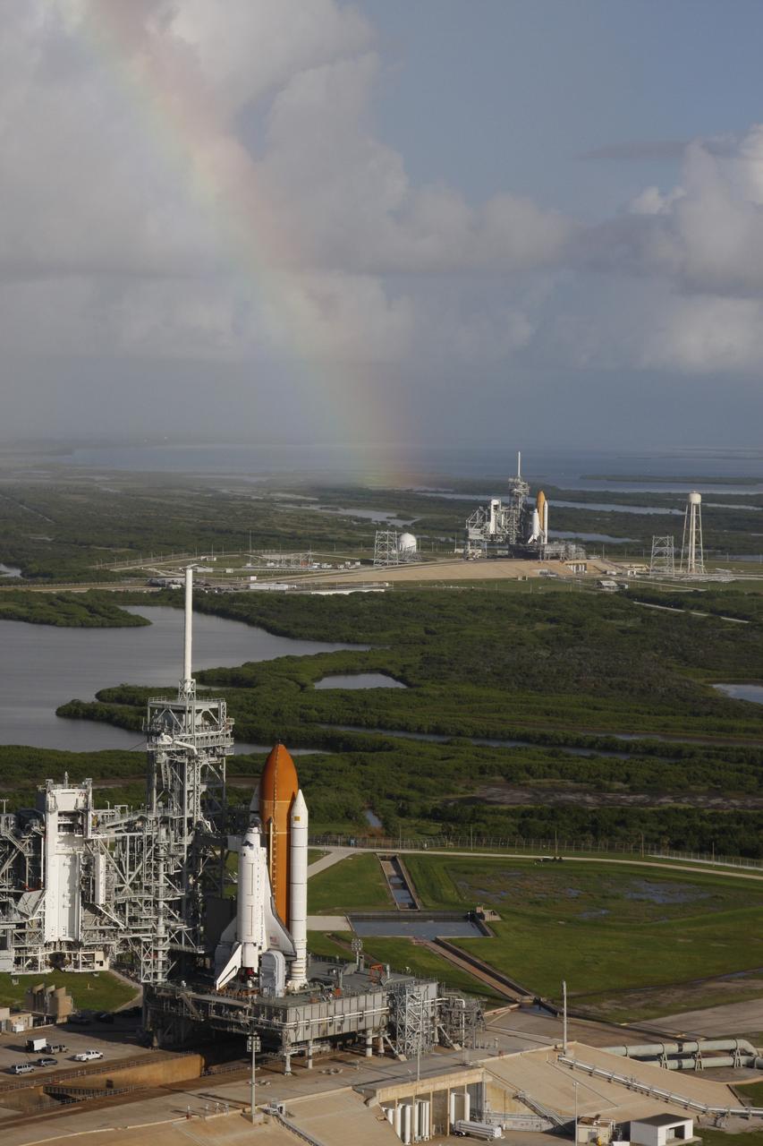 CAPE CANAVERAL, Fla. -  With a rainbow beginning to appear in the sky, space shuttle Atlantis (foreground) sits on Launch Pad A and Endeavour on Launch Pad B at NASA’s Kennedy Space Center in Florida. At the left of each shuttle are the open rotating service structures with the payload changeout rooms revealed. The rotating service structures provide protection for weather and access to the shuttle. For the first time since July 2001, two shuttles are on the launch pads at the same time at the center. Endeavour will stand by at pad B in the unlikely event that a rescue mission is necessary during space shuttle Atlantis’ upcoming mission to repair NASA’s Hubble Space Telescope, targeted to launch Oct. 10. After Endeavour is cleared from its duty as a rescue spacecraft, it will be moved to Launch Pad 39A for its STS-126 mission to the International Space Station. That flight is targeted for launch Nov. 12. Photo credit: NASA/Troy Cryder