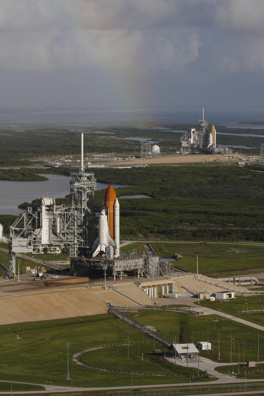 CAPE CANAVERAL, Fla. -  With a rainbow serving as a backdrop in the sky, space shuttle Atlantis (foreground) sits on Launch Pad A and Endeavour on Launch Pad B at NASA’s Kennedy Space Center in Florida. At the left of each shuttle are the open rotating service structures with the payload changeout rooms revealed. The rotating service structures provide protection for weather and access to the shuttle. For the first time since July 2001, two shuttles are on the launch pads at the same time at the center. Endeavour will stand by at pad B in the unlikely event that a rescue mission is necessary during space shuttle Atlantis’ upcoming mission to repair NASA’s Hubble Space Telescope, targeted to launch Oct. 10. After Endeavour is cleared from its duty as a rescue spacecraft, it will be moved to Launch Pad 39A for its STS-126 mission to the International Space Station. That flight is targeted for launch Nov. 12. Photo credit: NASA/Troy Cryder