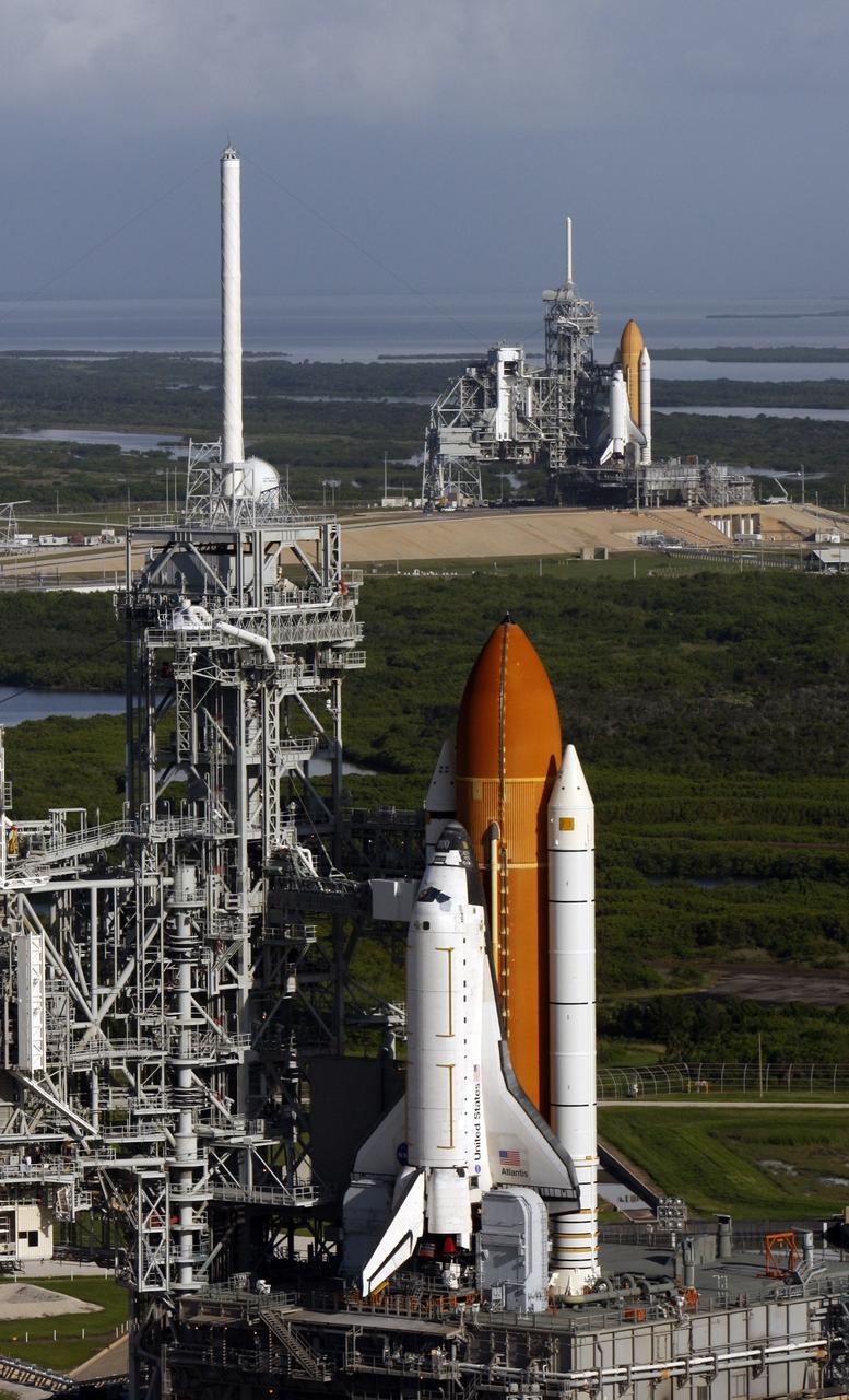 CAPE CANAVERAL, Fla. - Space shuttle Atlantis (foreground) sits on Launch Pad A and Endeavour on Launch Pad B at NASA’s Kennedy Space Center in Florida. At the left of each shuttle are the open rotating service structures with the payload changeout rooms revealed. The rotating service structures provide protection for weather and access to the shuttle. For the first time since July 2001, two shuttles are on the launch pads at the same time at the center. Endeavour will stand by at pad B in the unlikely event that a rescue mission is necessary during space shuttle Atlantis’ upcoming mission to repair NASA’s Hubble Space Telescope, targeted to launch Oct. 10. After Endeavour is cleared from its duty as a rescue spacecraft, it will be moved to Launch Pad 39A for its STS-126 mission to the International Space Station. That flight is targeted for launch Nov. 12. Photo credit: NASA/Troy Cryder
