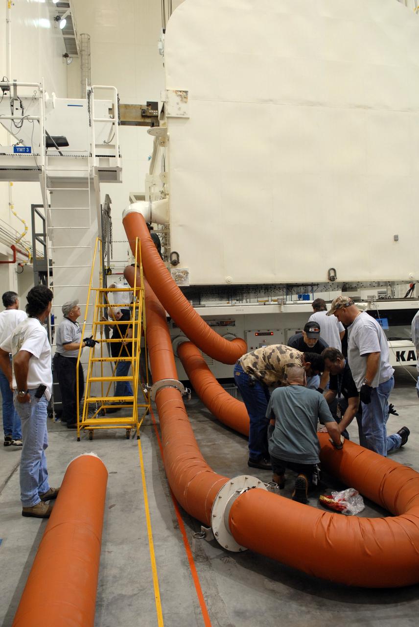 CAPE CANAVERAL, Fla. -  At NASA's Kennedy Space Center, the payload canister is in the Canister Rotation Facility where it will be lifted to a vertical position.  Workers check the umbilical lines that keep a controlled environment in the canister.  The canister’s cargo consists of four carriers holding various equipment for the STS-125 mission aboard space shuttle Atlantis to service NASA’s Hubble Space Telescope. At the pad, the cargo will be moved into the Payload Changeout Room.  The changeout room is the enclosed, environmentally controlled portion of the rotating service structure that supports cargo delivery to the pad and subsequent vertical installation into the shuttle’s payload bay. Launch of Atlantis is targeted for Oct. 10.   Photo credit: NASA/Jack Pfaller