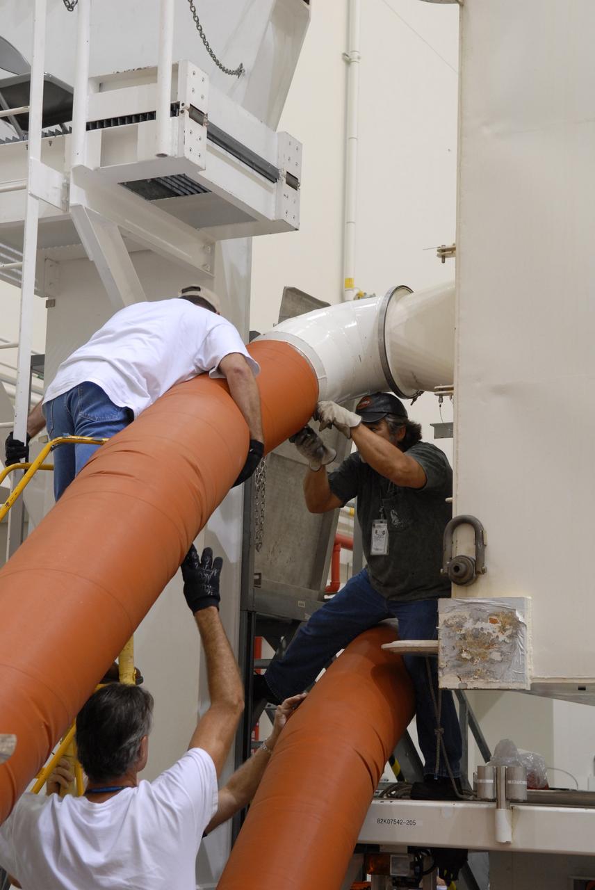 CAPE CANAVERAL, Fla. -   In the Canister Rotation Facility at NASA's Kennedy Space Center, workers check the umbilical lines that keep a controlled environment in the payload canister.  The canister will be lifted to a vertical position for the trip to Launch Pad 39A. The canister’s cargo consists of four carriers holding various equipment for the STS-125 mission aboard space shuttle Atlantis to service NASA’s Hubble Space Telescope.  At the pad, the cargo will be moved into the Payload Changeout Room.  The changeout room is the enclosed, environmentally controlled portion of the rotating service structure that supports cargo delivery to the pad and subsequent vertical installation into the shuttle’s payload bay. Launch of Atlantis is targeted for Oct. 10.   Photo credit: NASA/Jack Pfaller