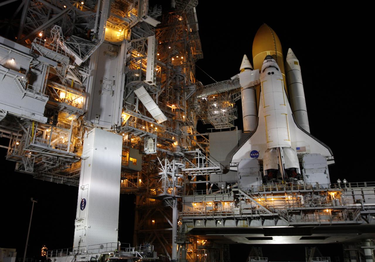 CAPE CANAVERAL, Fla. - At Launch Pad 39A at NASA's Kennedy Space Center in Florida, the payload canister arrives beneath the payload changeout room in the rotating service structure (left). Space shuttle Atlantis is at right. The two tail service masts on the mobile launcher platform flank the engines in front of the wings. The canister carries a cargo of four carriers holding various equipment for the STS-125 mission aboard Atlantis to service NASA’s Hubble Space Telescope. At the pad, the cargo will be moved into the Payload Changeout Room. The changeout room is the enclosed, environmentally controlled portion of the rotating service structure that supports cargo delivery to the pad and subsequent vertical installation into the shuttle’s payload bay. Launch of Atlantis is targeted for Oct. 10. Photo credit: NASA/Troy Cryder