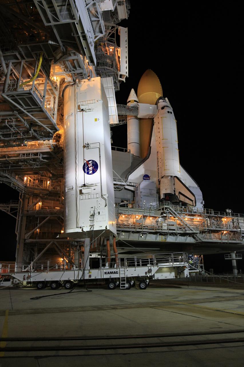 CAPE CANAVERAL, Fla. - At Launch Pad 39A at NASA's Kennedy Space Center in Florida, the payload canister, at left, is lifted from its transporter toward the payload changeout room in the rotating service structure. The canister carries a cargo of four carriers holding various equipment for the STS-125 mission aboard space shuttle Atlantis to service NASA’s Hubble Space Telescope. Atlantis is seen at right, atop the mobile launcher platform. The two tail service masts flank the engines in front of the wings. At the pad, the cargo will be moved into the Payload Changeout Room. The changeout room is the enclosed, environmentally controlled portion of the rotating service structure that supports cargo delivery to the pad and subsequent vertical installation into the shuttle’s payload bay. Launch of Atlantis is targeted for Oct. 10. Photo credit: NASA/Troy Cryder